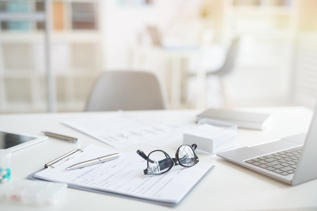 A well-organized workspace featuring a laptop, glasses, a pen, and documents with notes, symbolizing diligent preparation and detailed legal consultation provided by SAA Law Firm.