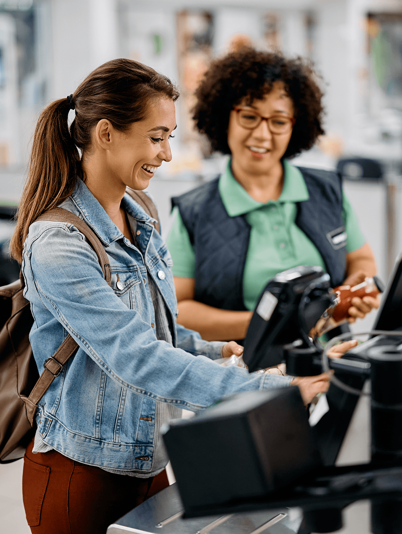 store worker helping at a self checkout kiosk