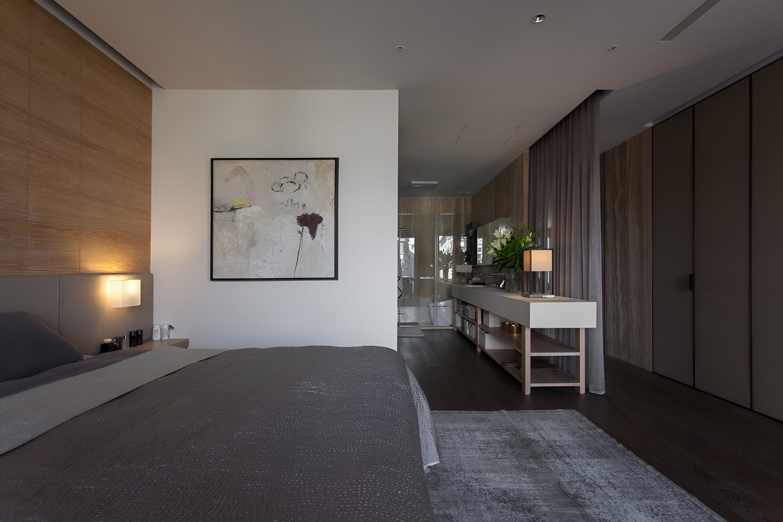 現代臥室設計搭配木質牆面與抽象畫作，延伸至玻璃隔間的浴室空間營造開放感