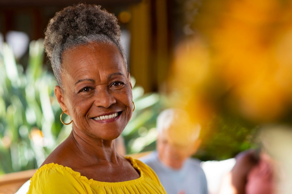 Smiling senior woman in a yellow top enjoying a sunny day outdoors