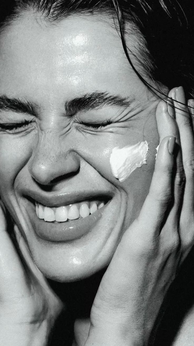 A luxurious bathtub filled with water and floating rose petals, surrounded by candles and greenery. The soft lighting creates a tranquil and romantic spa-like atmosphere.
