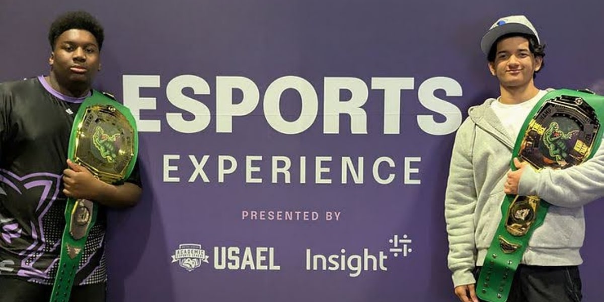 two champions proudly holding their belts at the Stomp in the Swamp esports competition, celebrating their victories.