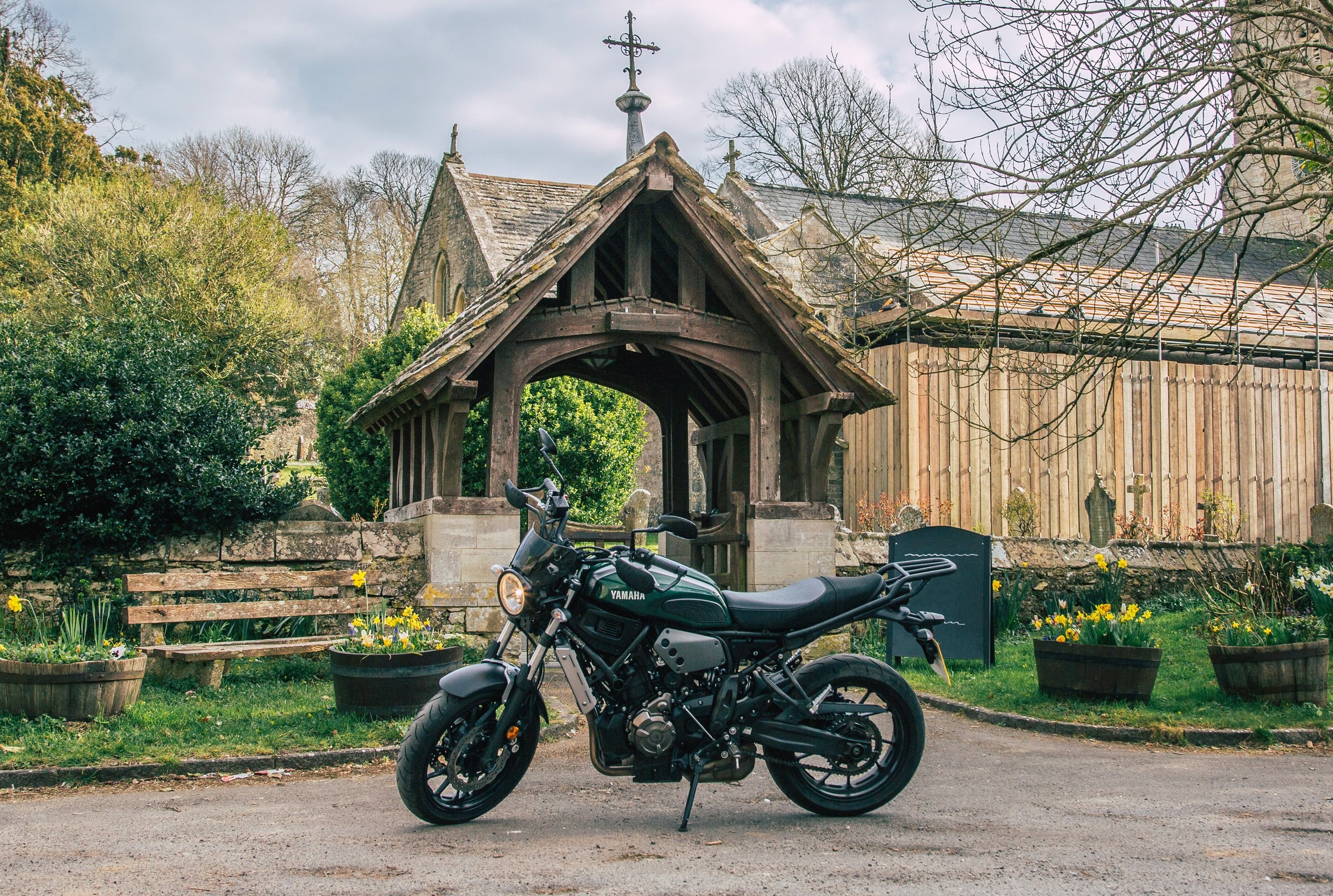 TRAVEL · A motorbike beside a timber-framed church porch.