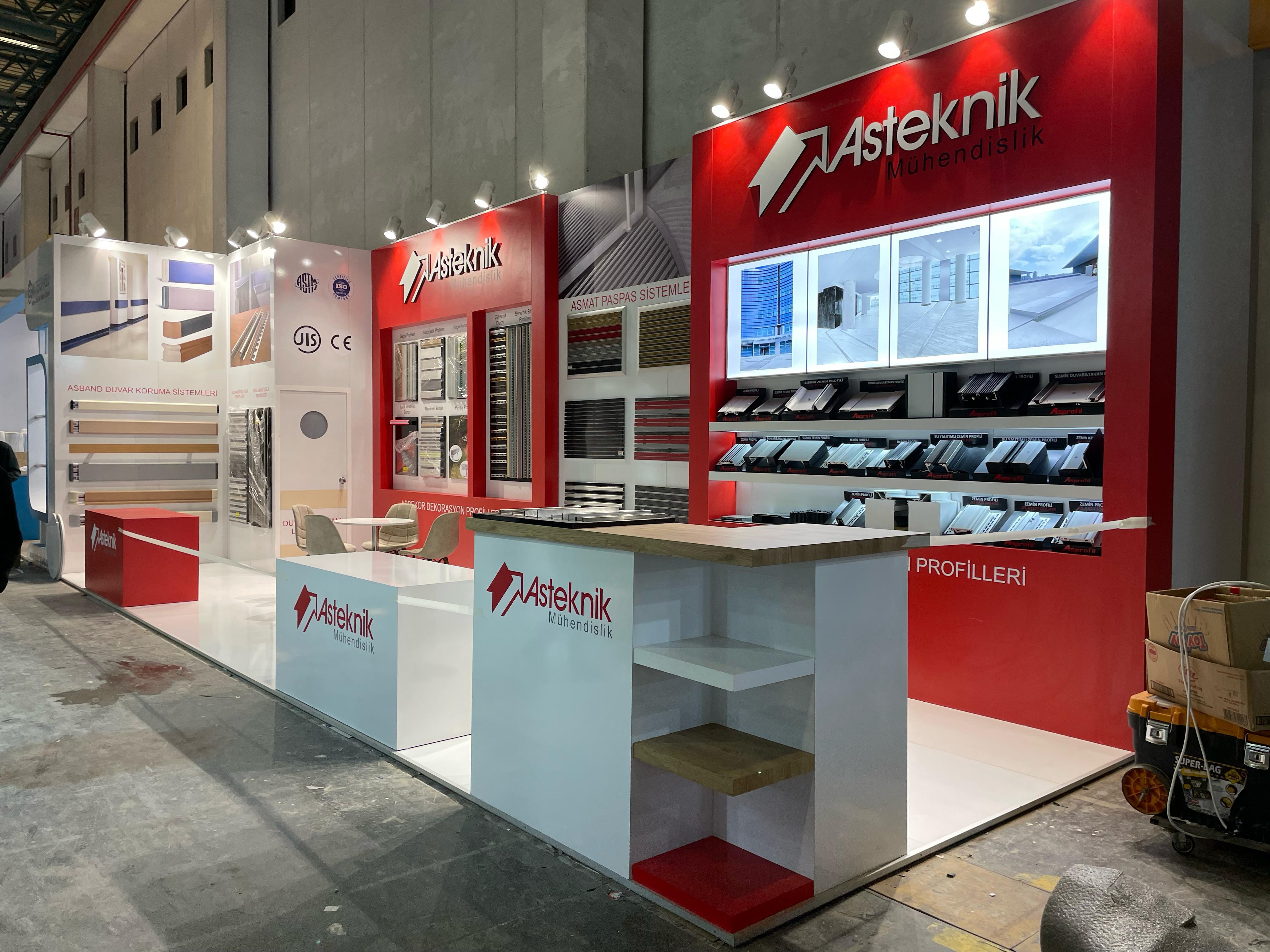 Alternate view of the Asteknik stand showing the overall layout, glossy white flooring, and organised product presentations.