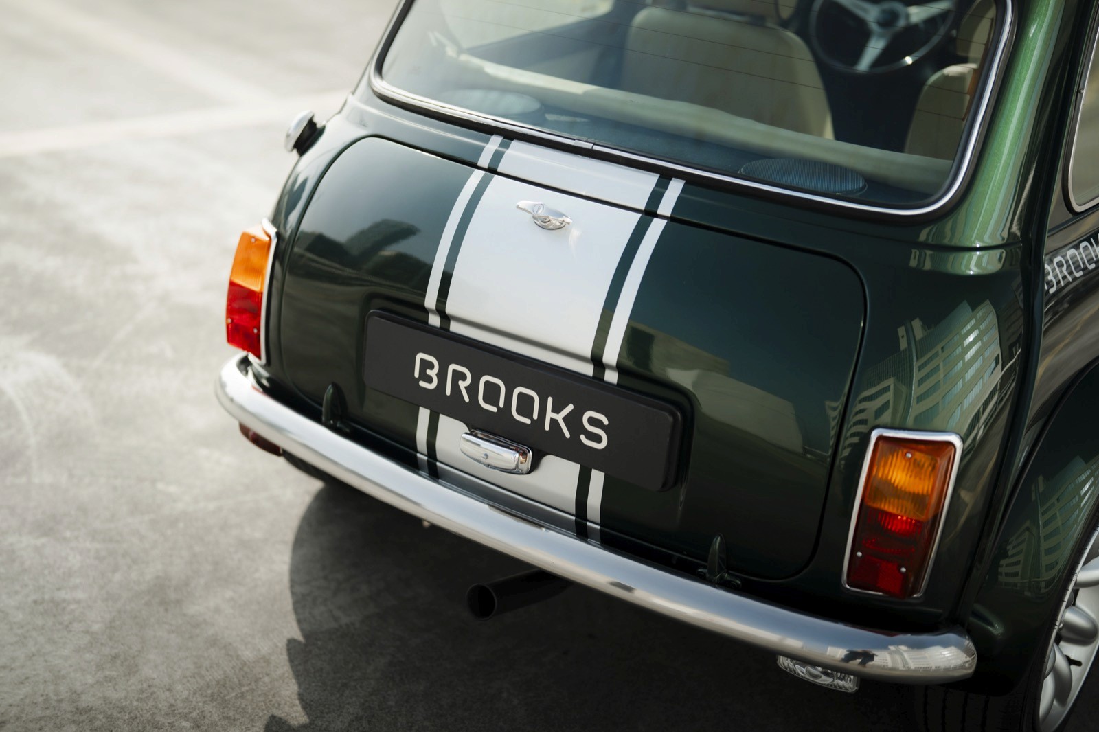 Close-up of the back of a vintage green car with a silver bumper and license plate visible.