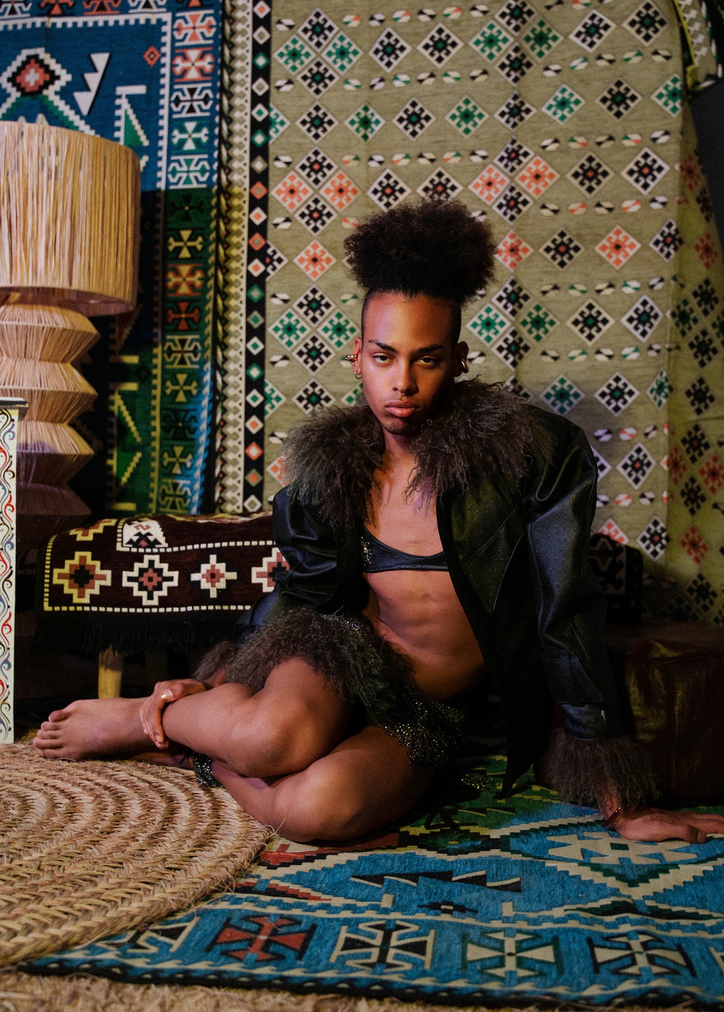 Model in dark fur outerwear crouching on a traditional patterned rug for Haytem.