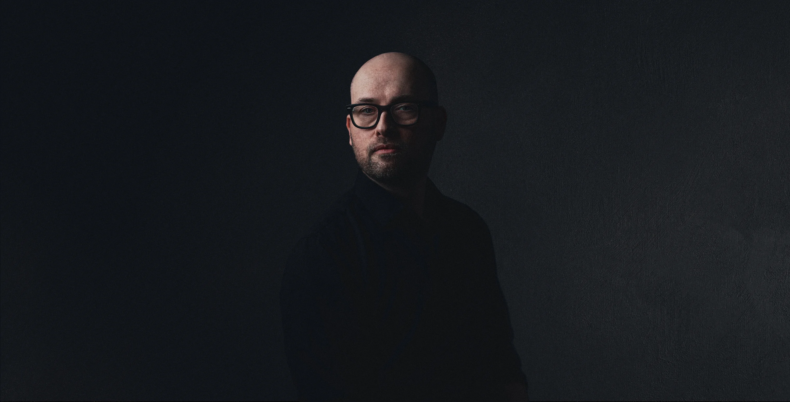 Portrait of Paul Johns, graphic designer, against a dark background