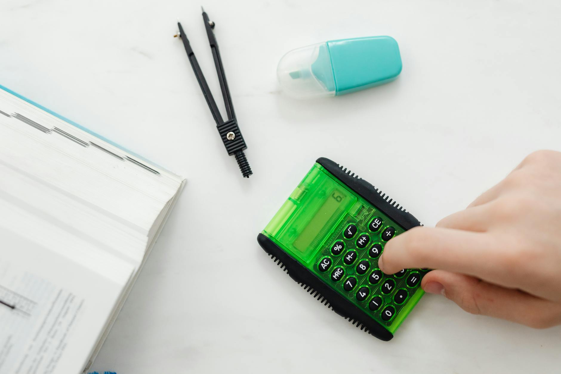 Close-up of a student's hands using colorful plastic base-ten blocks to solve a complex addition problem on a wooden desk.
