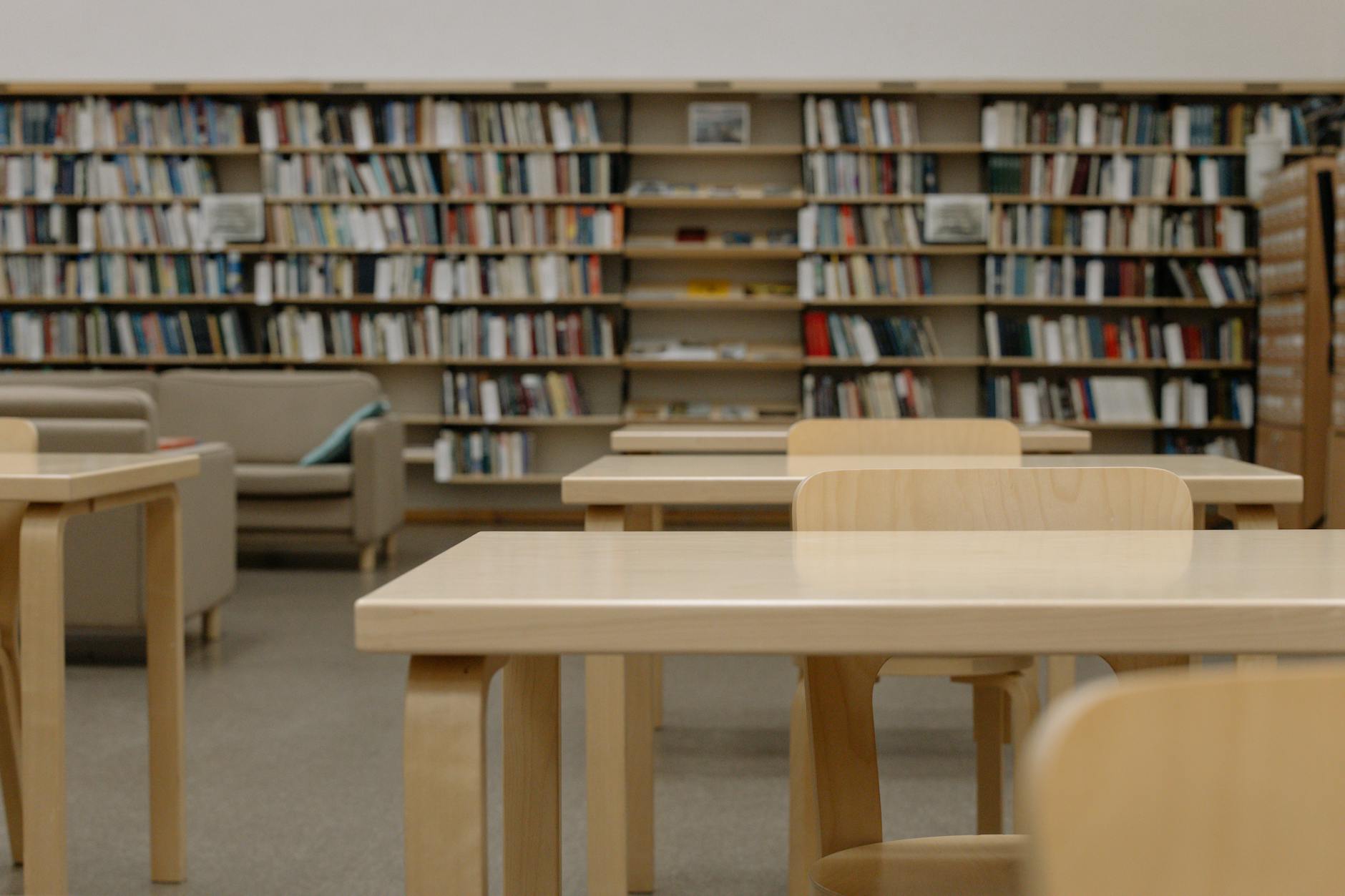 A group of diverse students smiling and walking through a bright university hallway with backpacks.