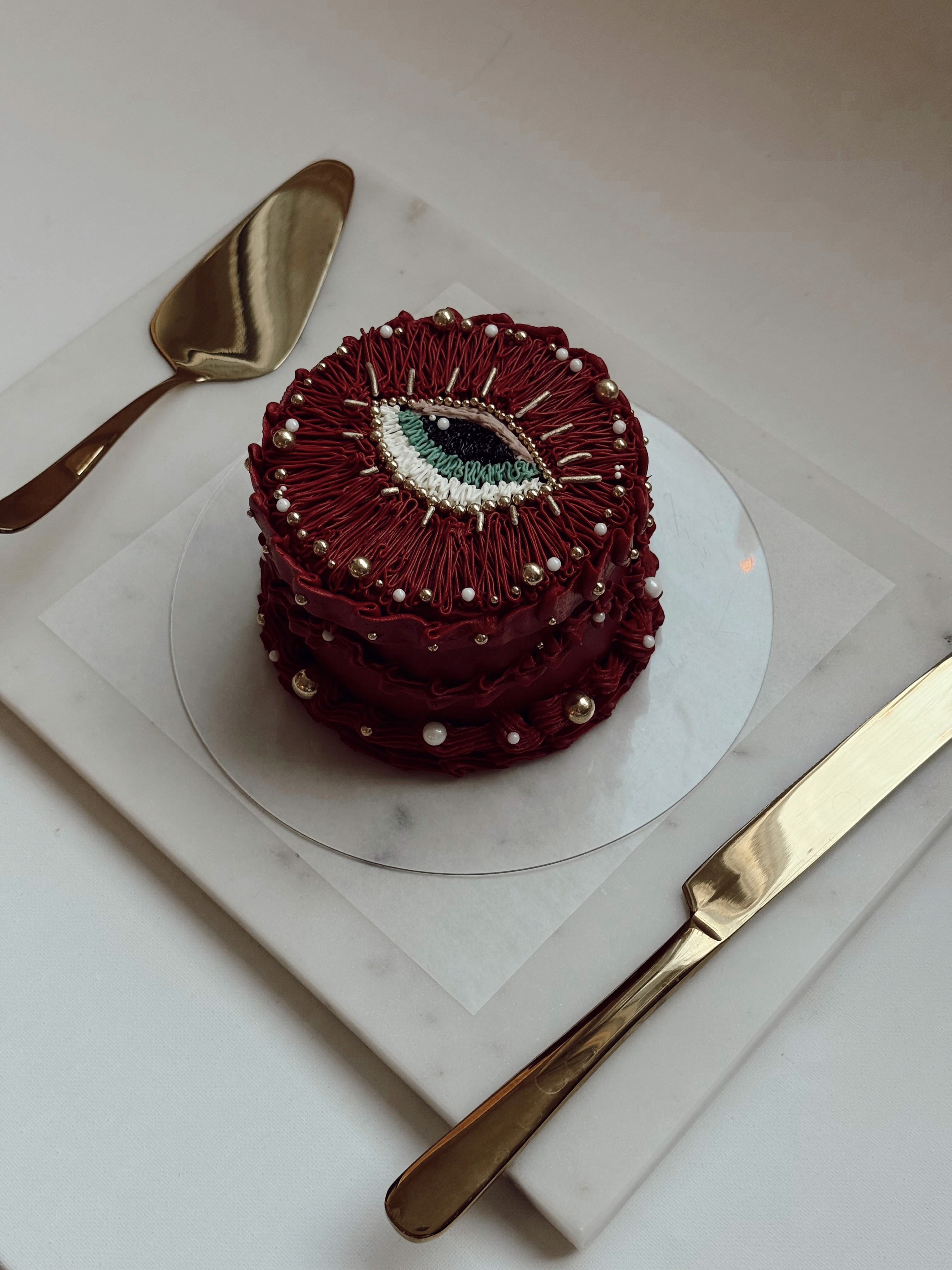 Dark red textured buttercream cake with an edible eye detail