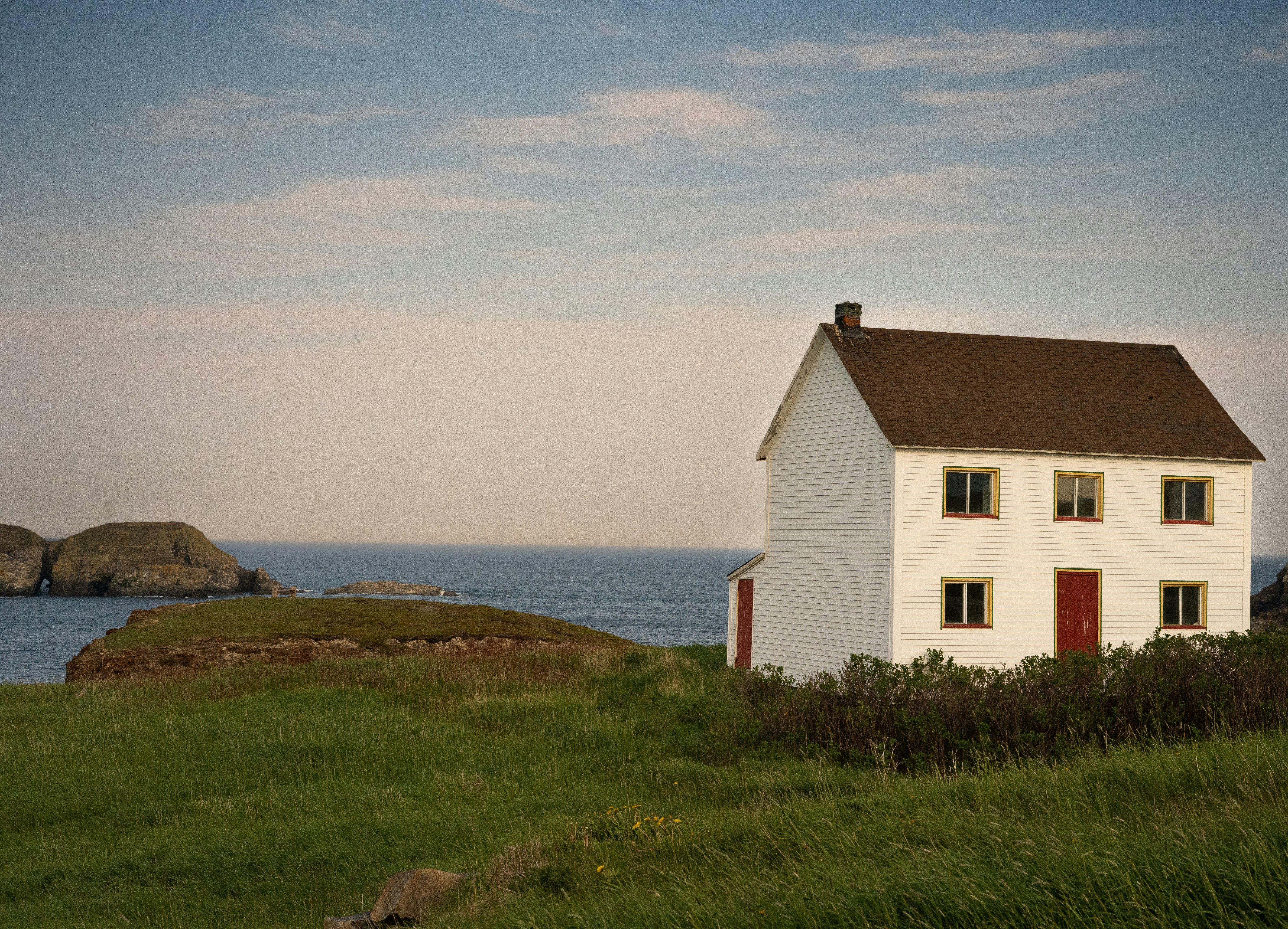 A white house sits by the ocean.