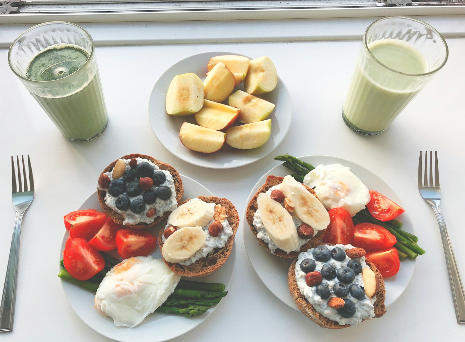 Balanced breakfast plates pairing protein and carbs, with eggs, whole-grain toast, banana, berries and green smoothies