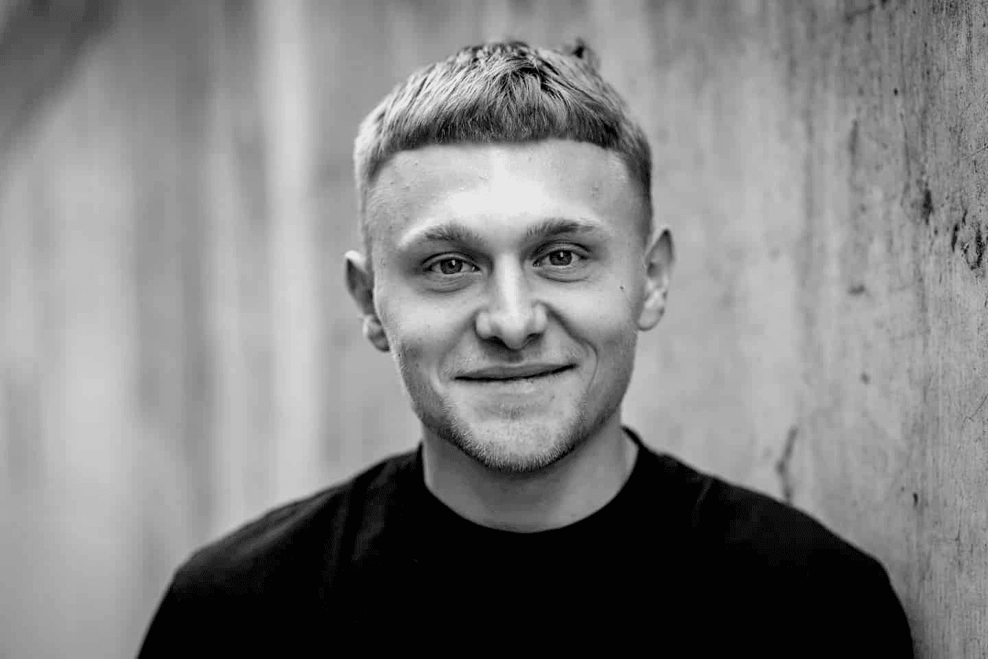 A woman stands beside an old projector, gazing at the camera. The scene is lit with teal and red hues, creating a mysterious and artistic atmosphere.