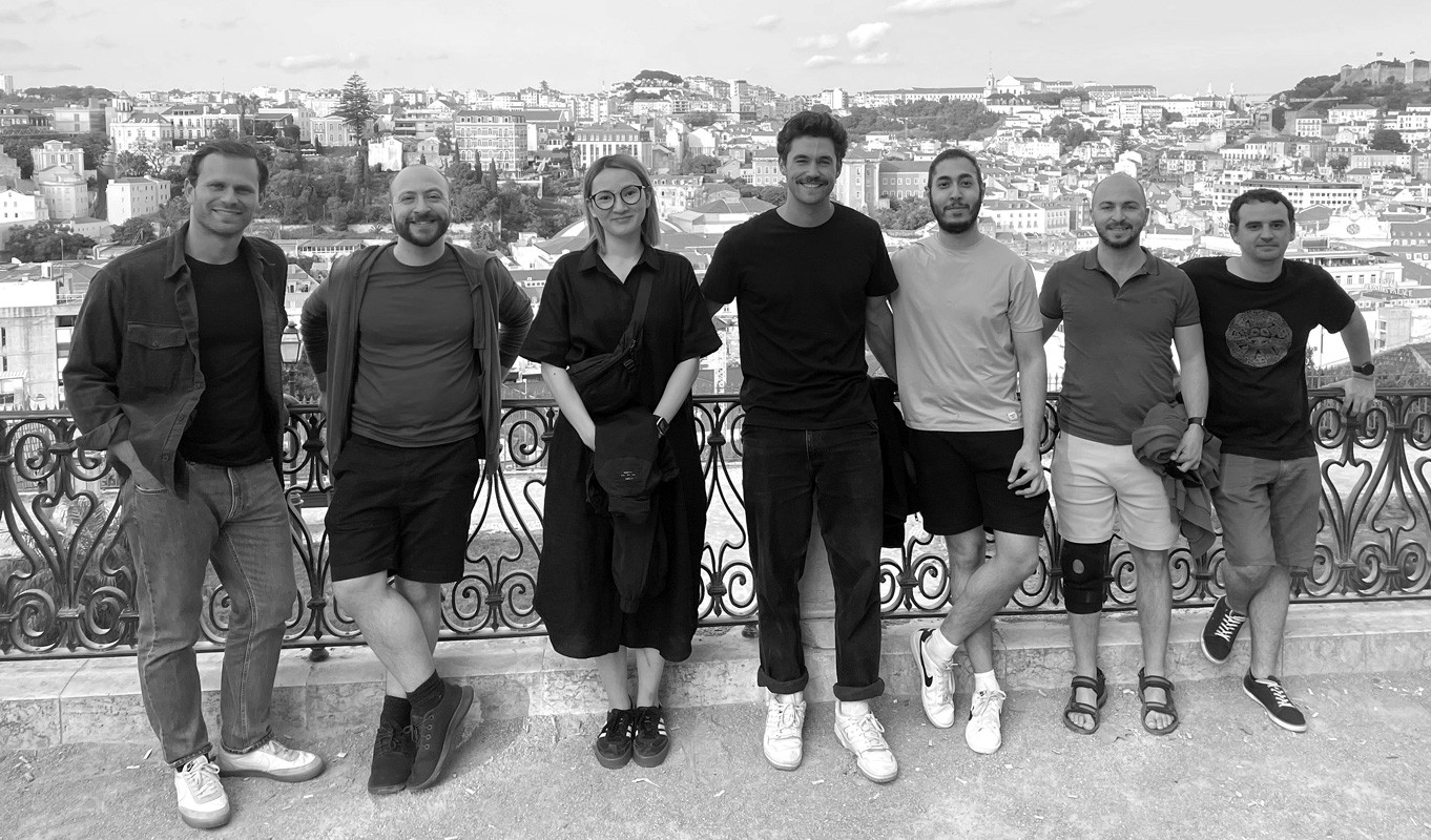 A screenshot of two GitBook team members working on laptops with mountains in the background