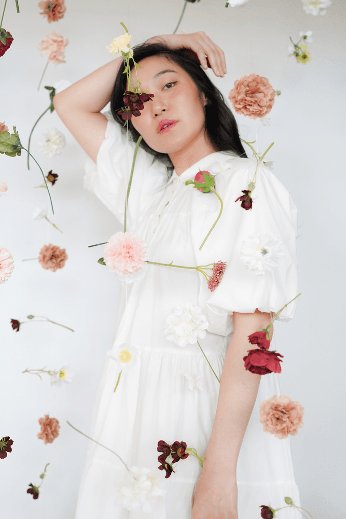 Person posing with flowers floating in the foreground