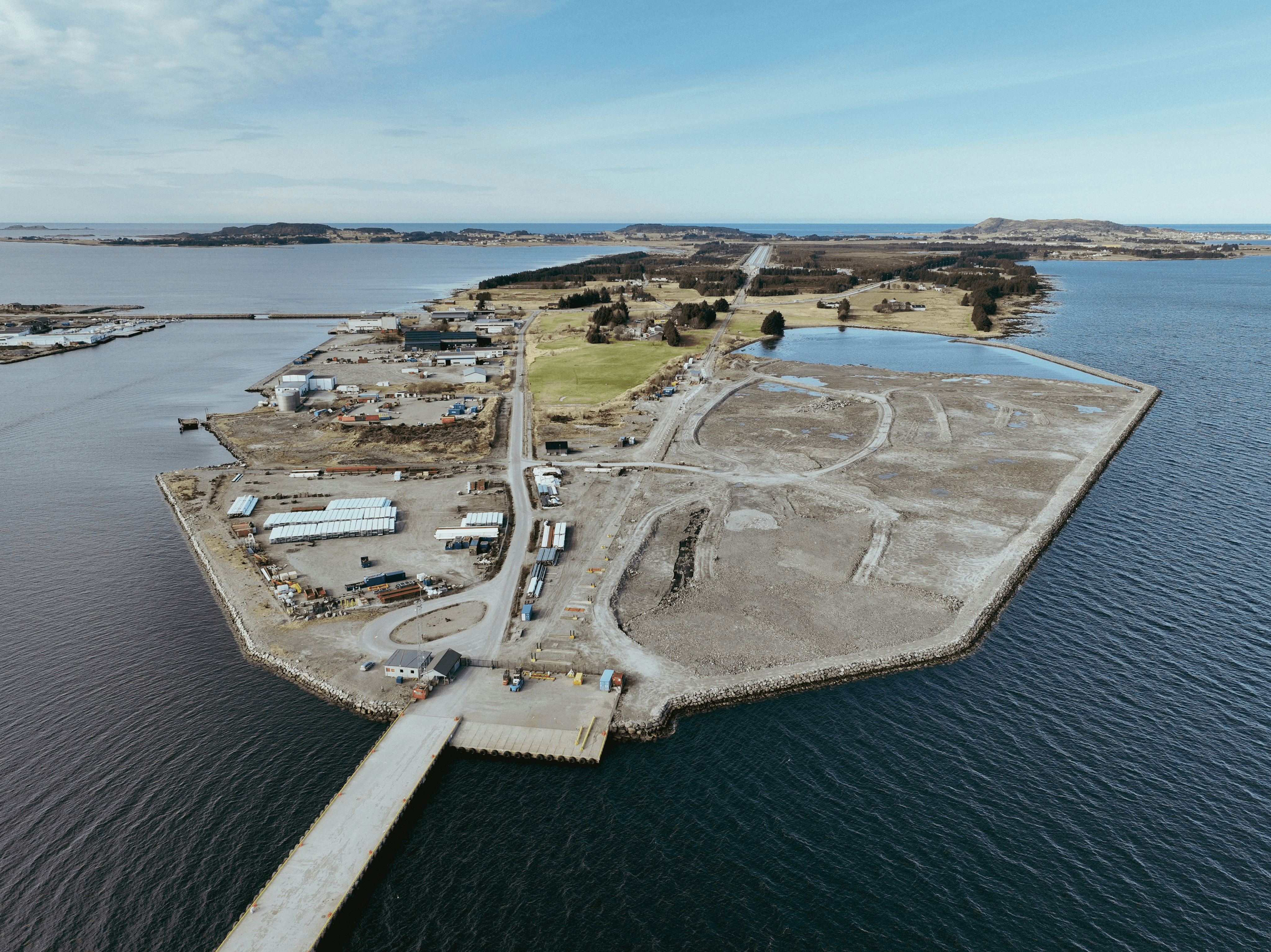 Aerial view of a coastal area with a rocky shoreline and a path leading to a structure on the land.