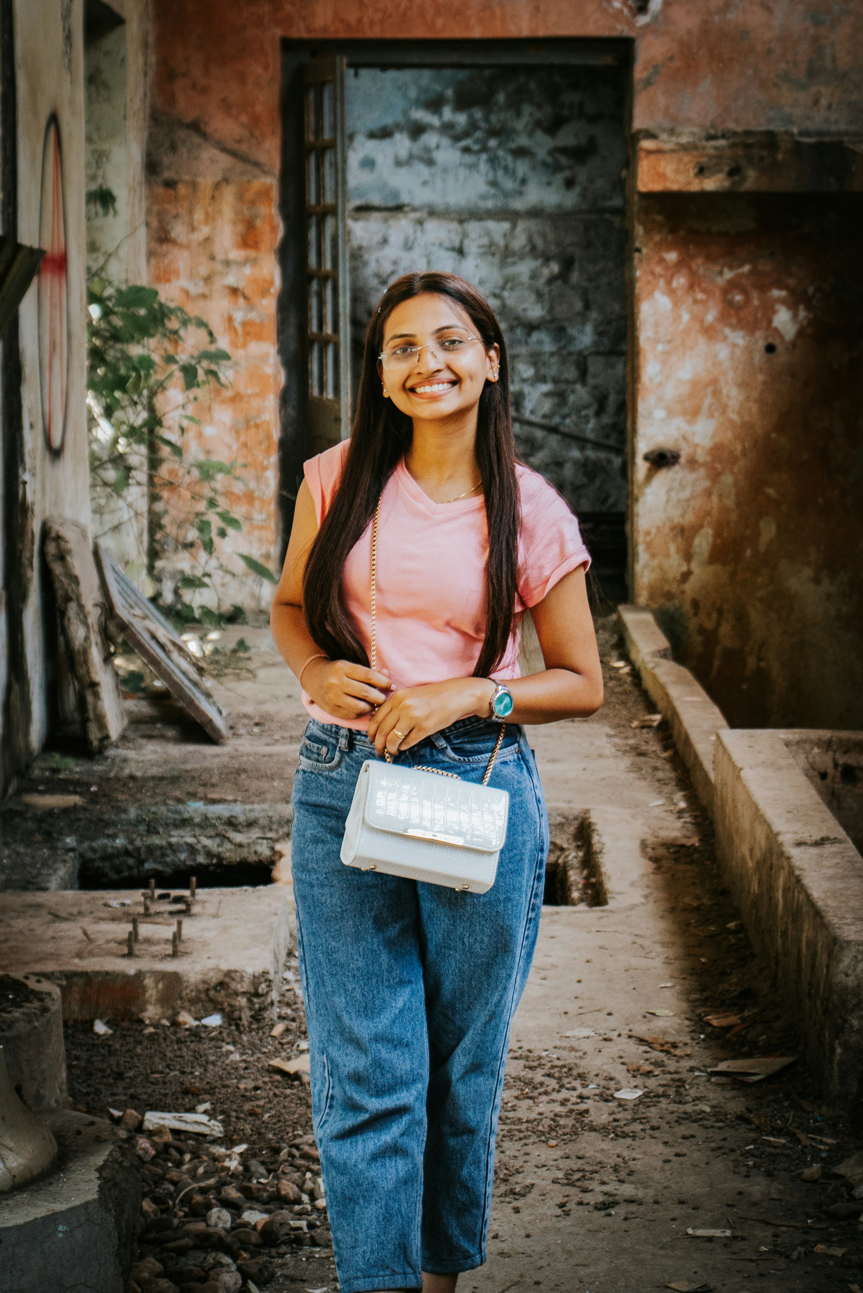 A woman standing in an alley with a white purse