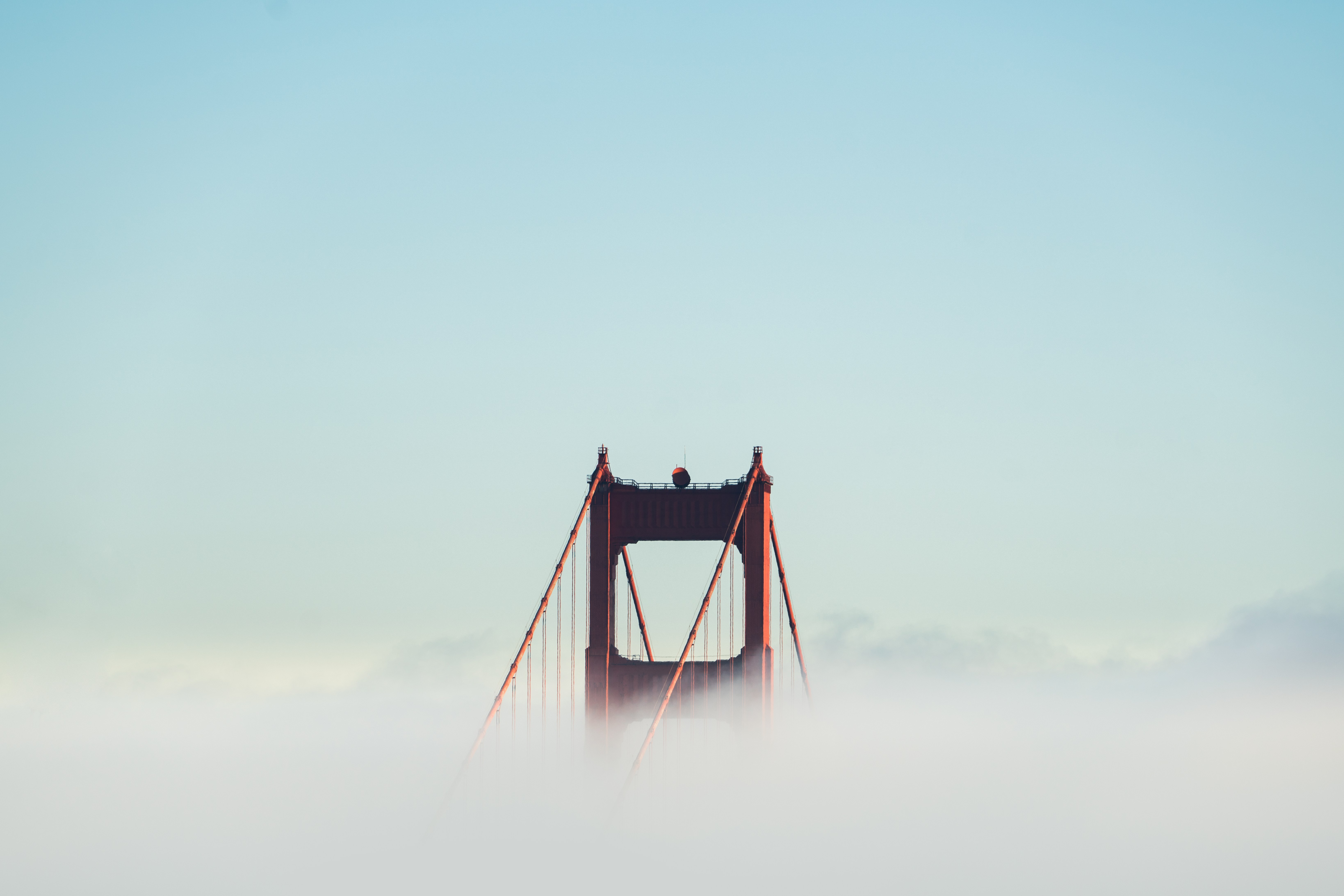 red concrete bridge surrounded by clouds