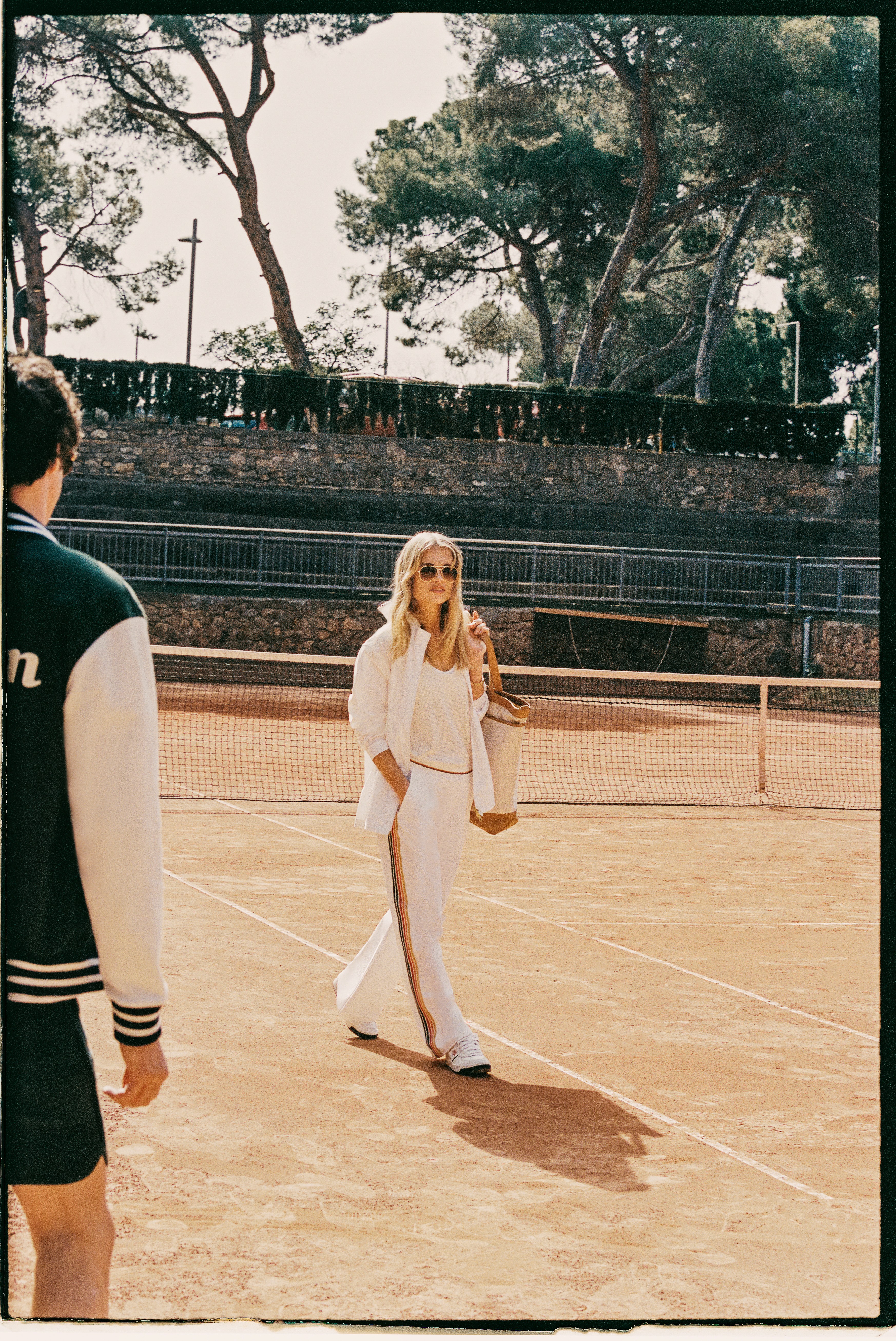Deux mannequins habillés en Wilson Sportstyle sur un court de tennis, portant jogging fluide de la marque en blanc et vert