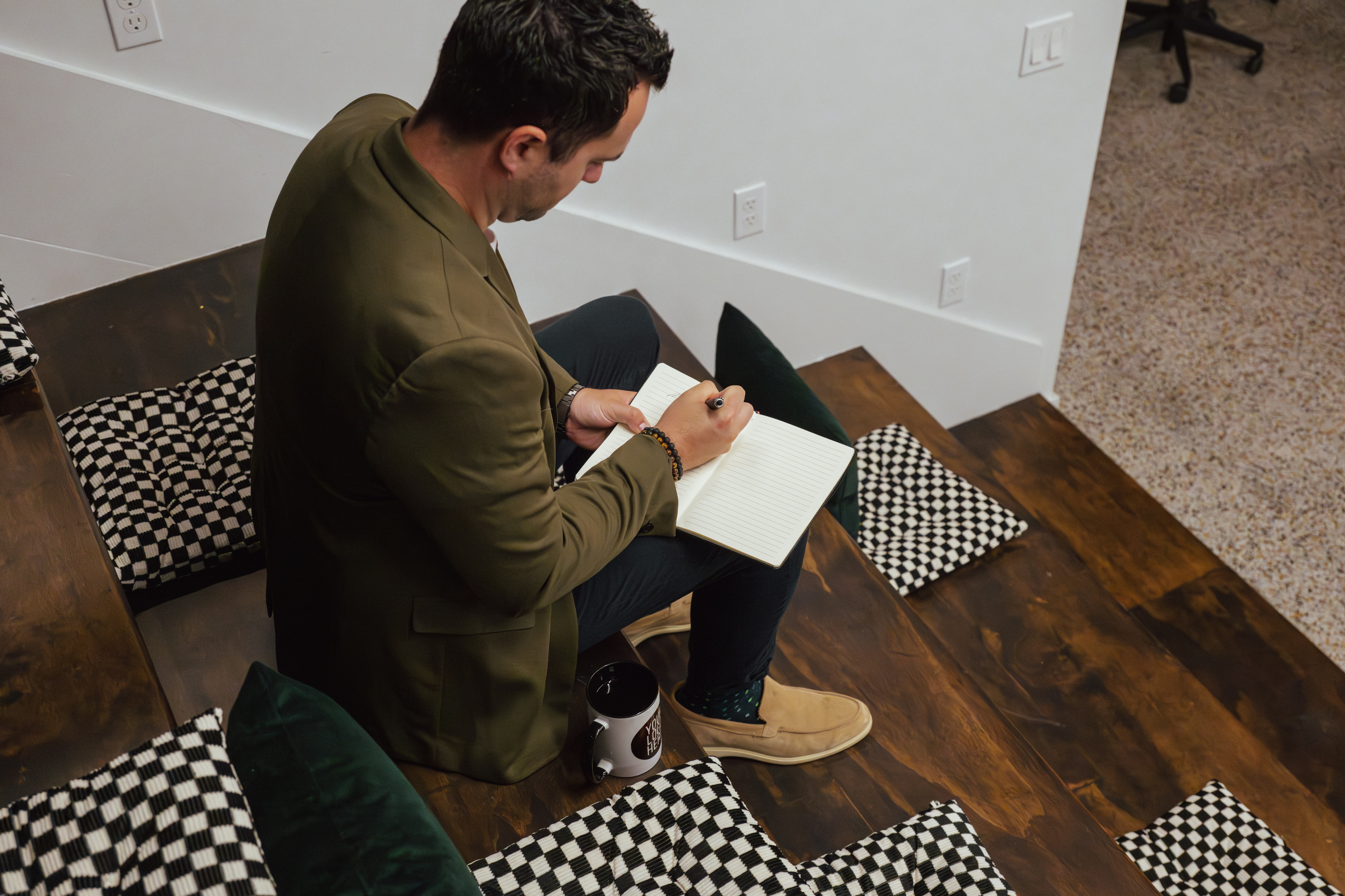 Man writing in a notebook while sitting on wooden stairs.