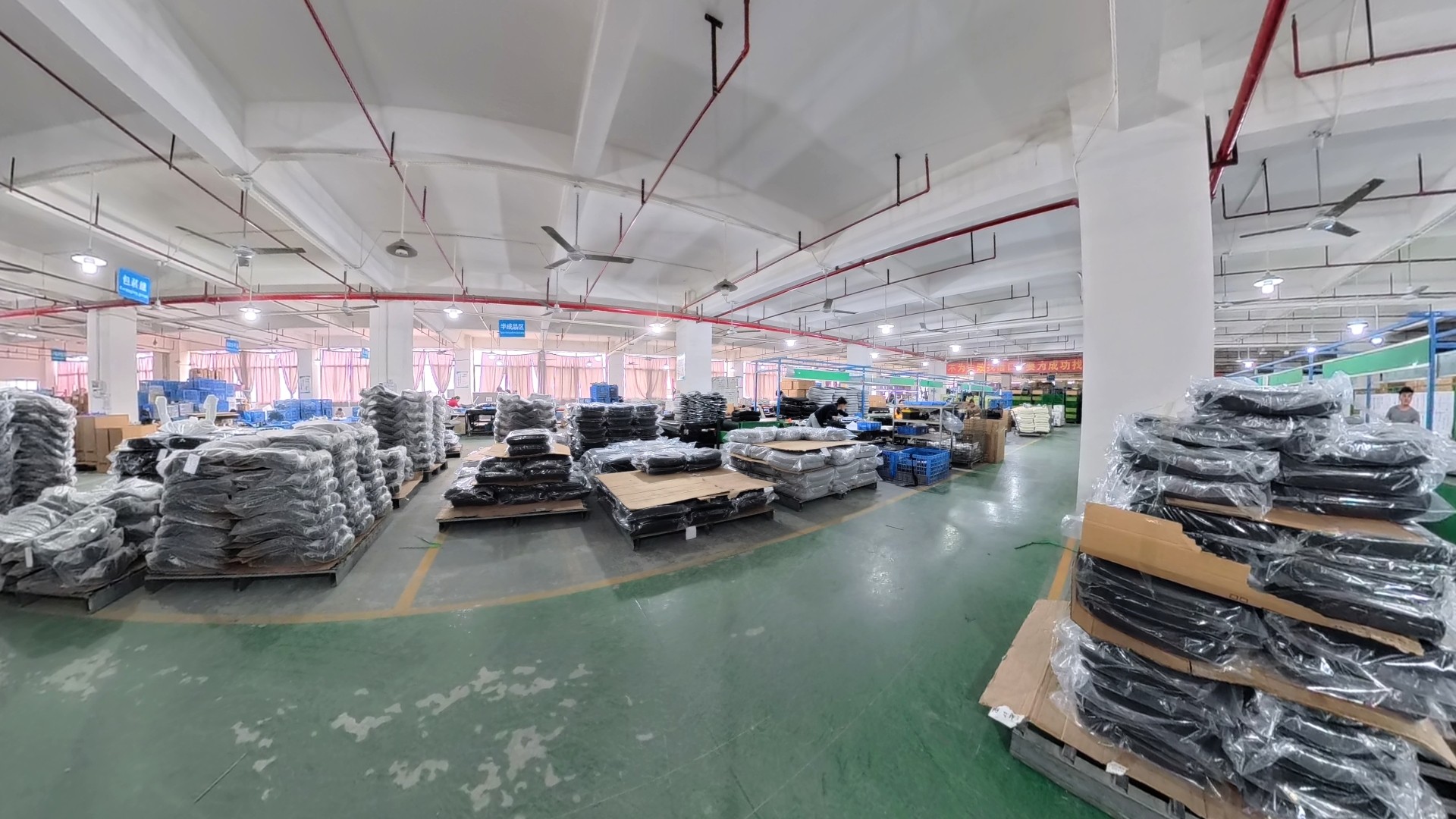 Large-scale office chair manufacturing factory floor at T-Chod Furniture, showing organized production lines, stacked ergonomic chair components in protective packaging, and professional furniture assembly workstations in a clean industrial facility.