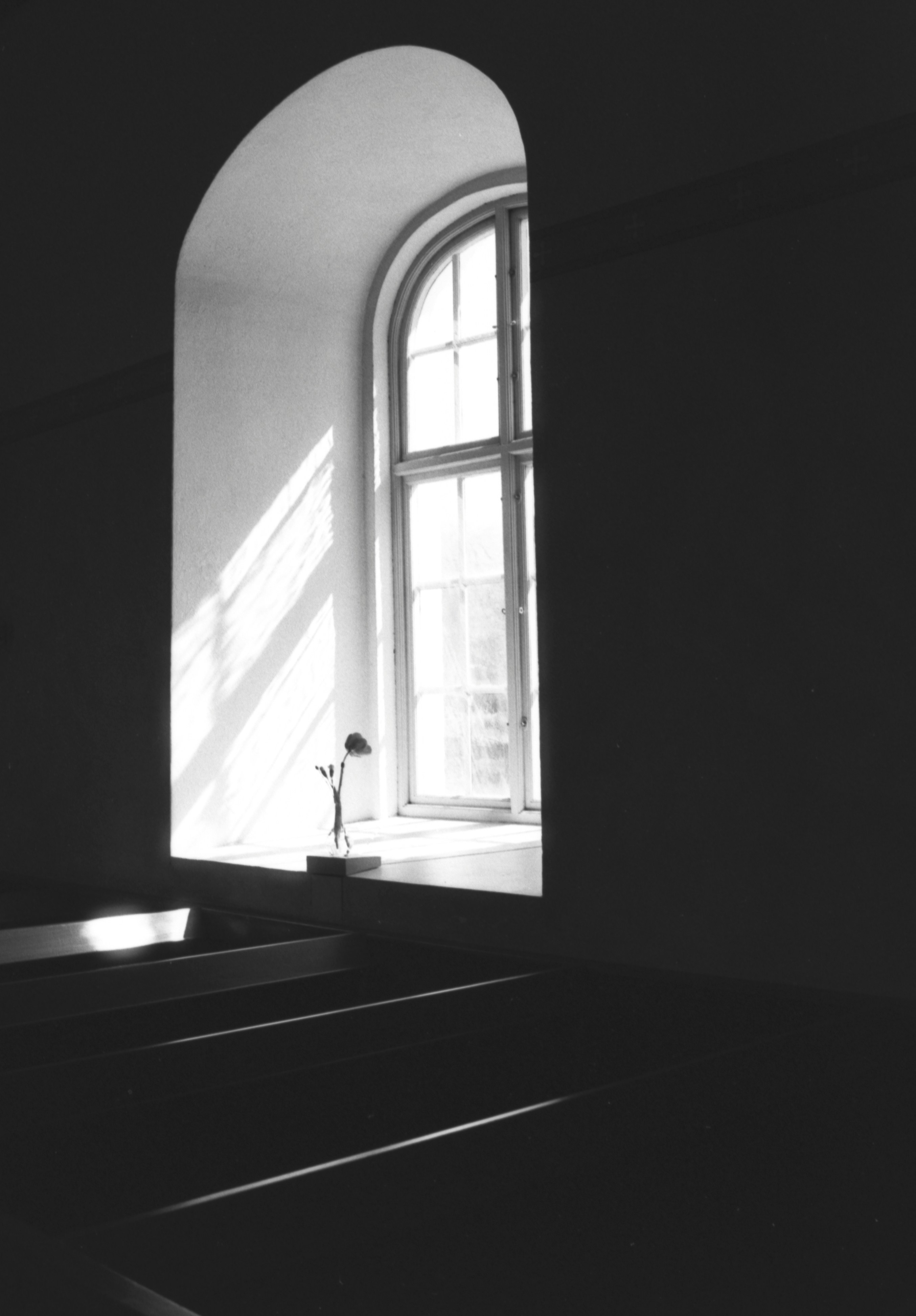 Sunlight streams through an arched window onto a ledge.