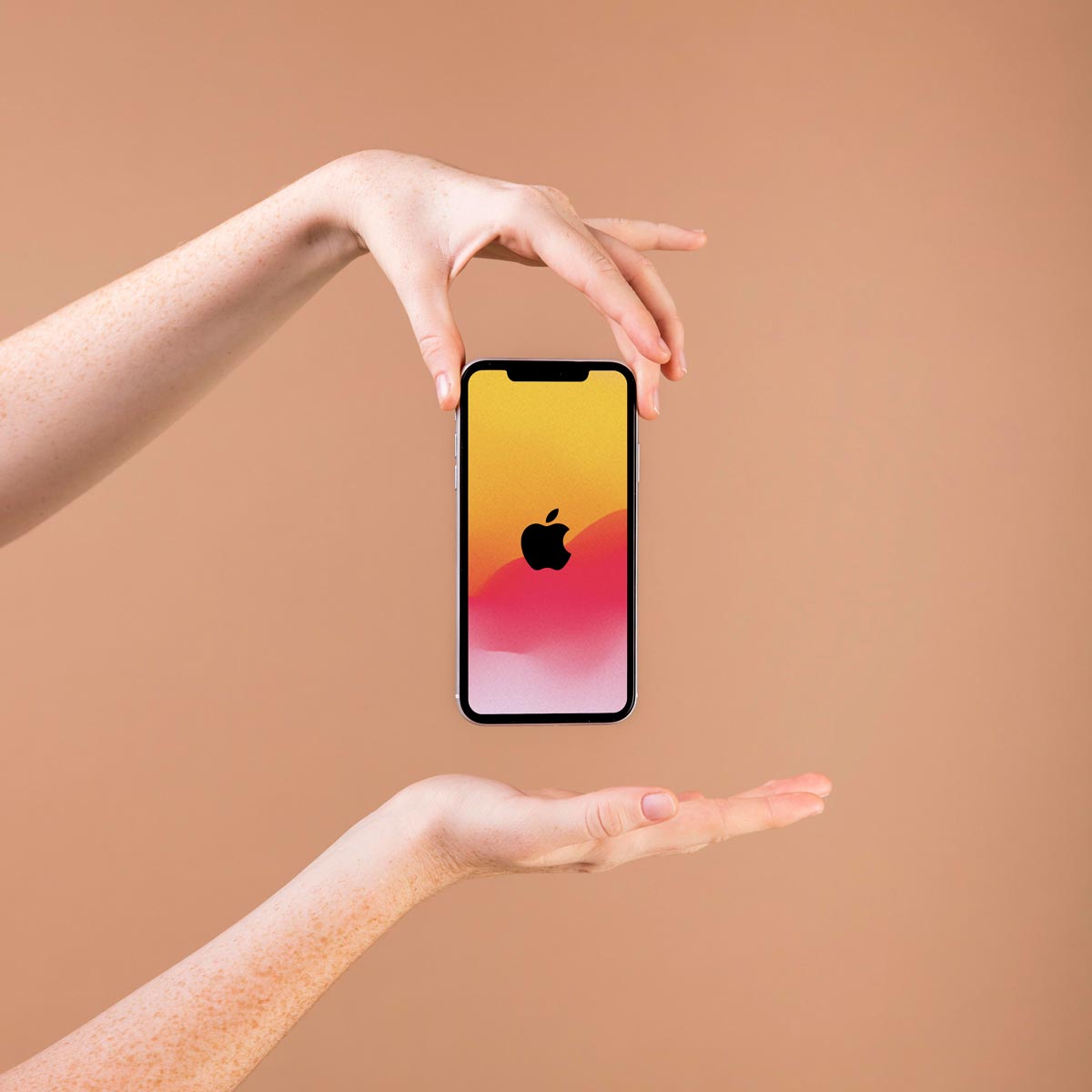 two hands holding an iPhone with the apple logo clearly displayed