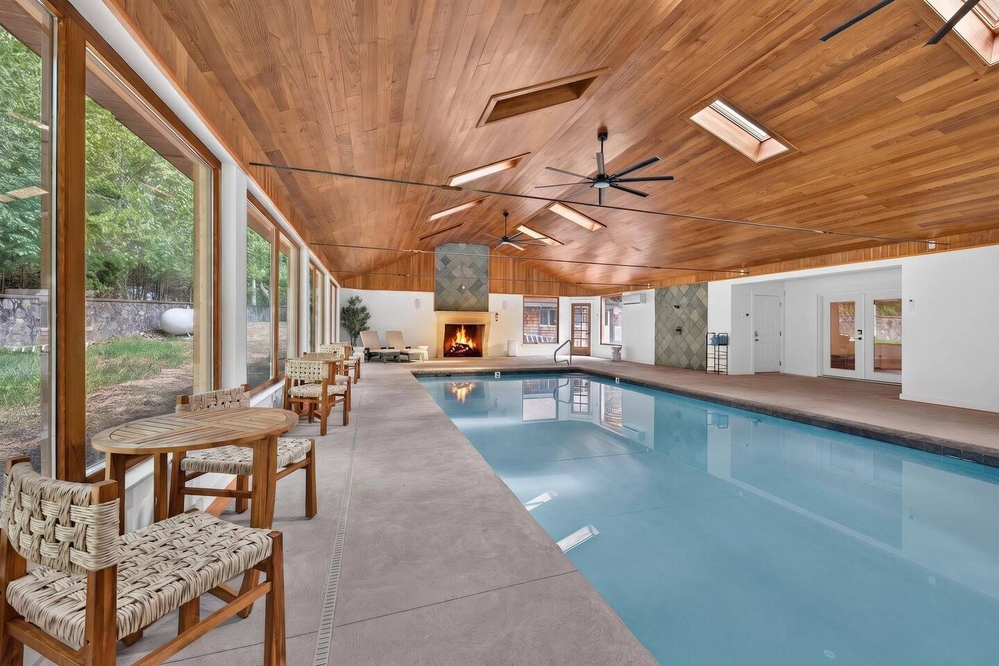 Poolside tables by the windows with the fireplace at the end of the hall