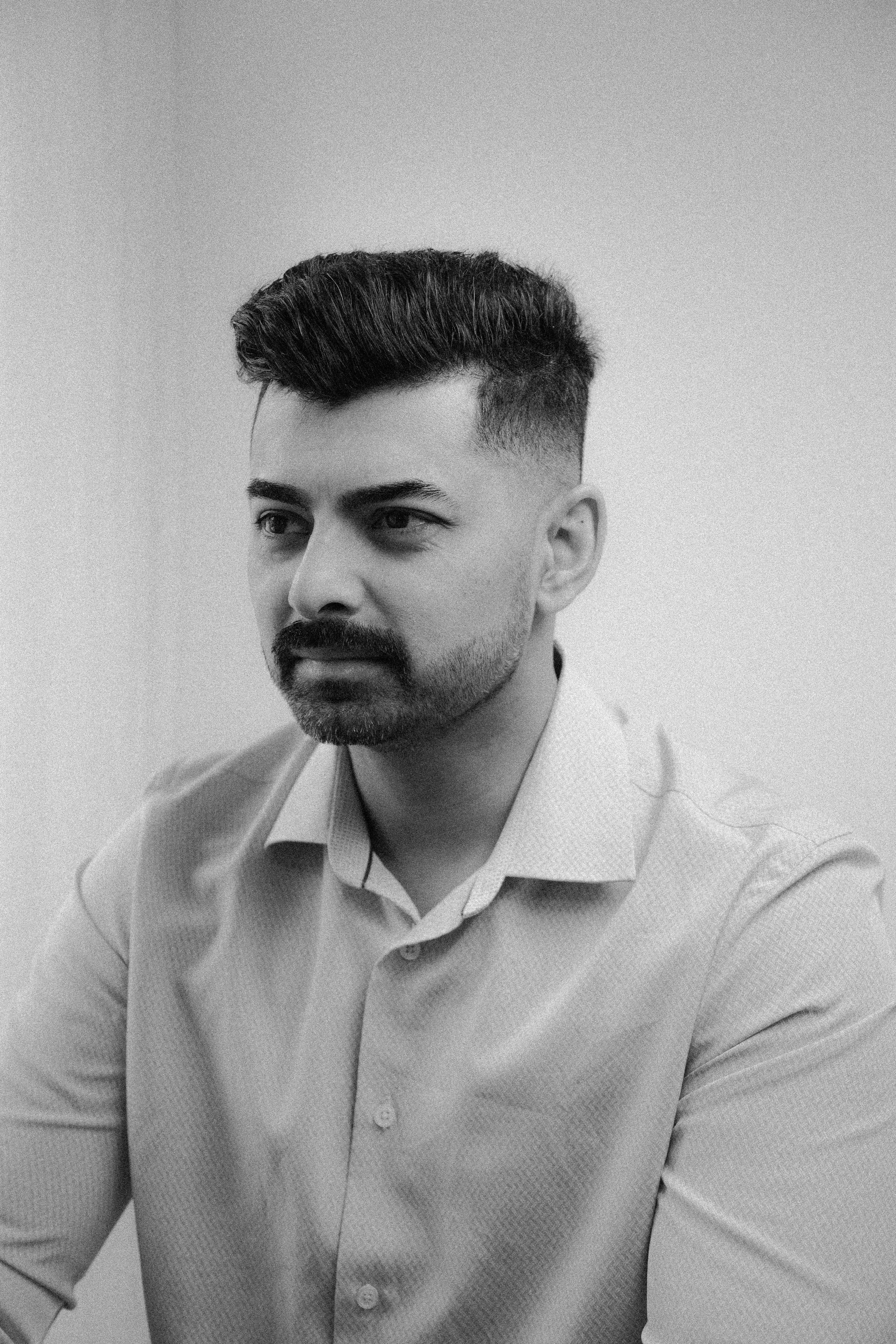 Woman with a short haircut smiling confidently, wearing a blazer and standing in warm natural light with modern architecture behind her.