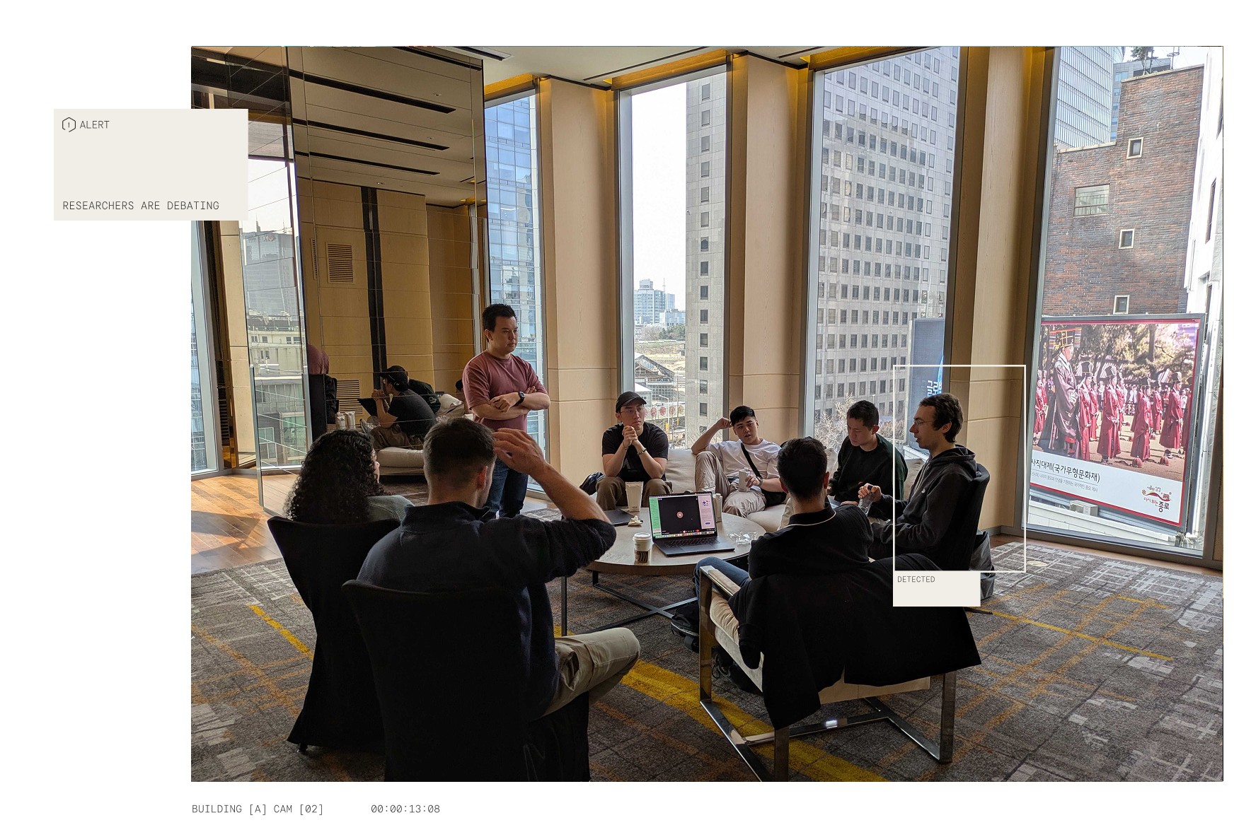 A group of people sitting in a circle in a modern office with floor-to-ceiling windows, engaged in a collaborative discussion during a hackathon.