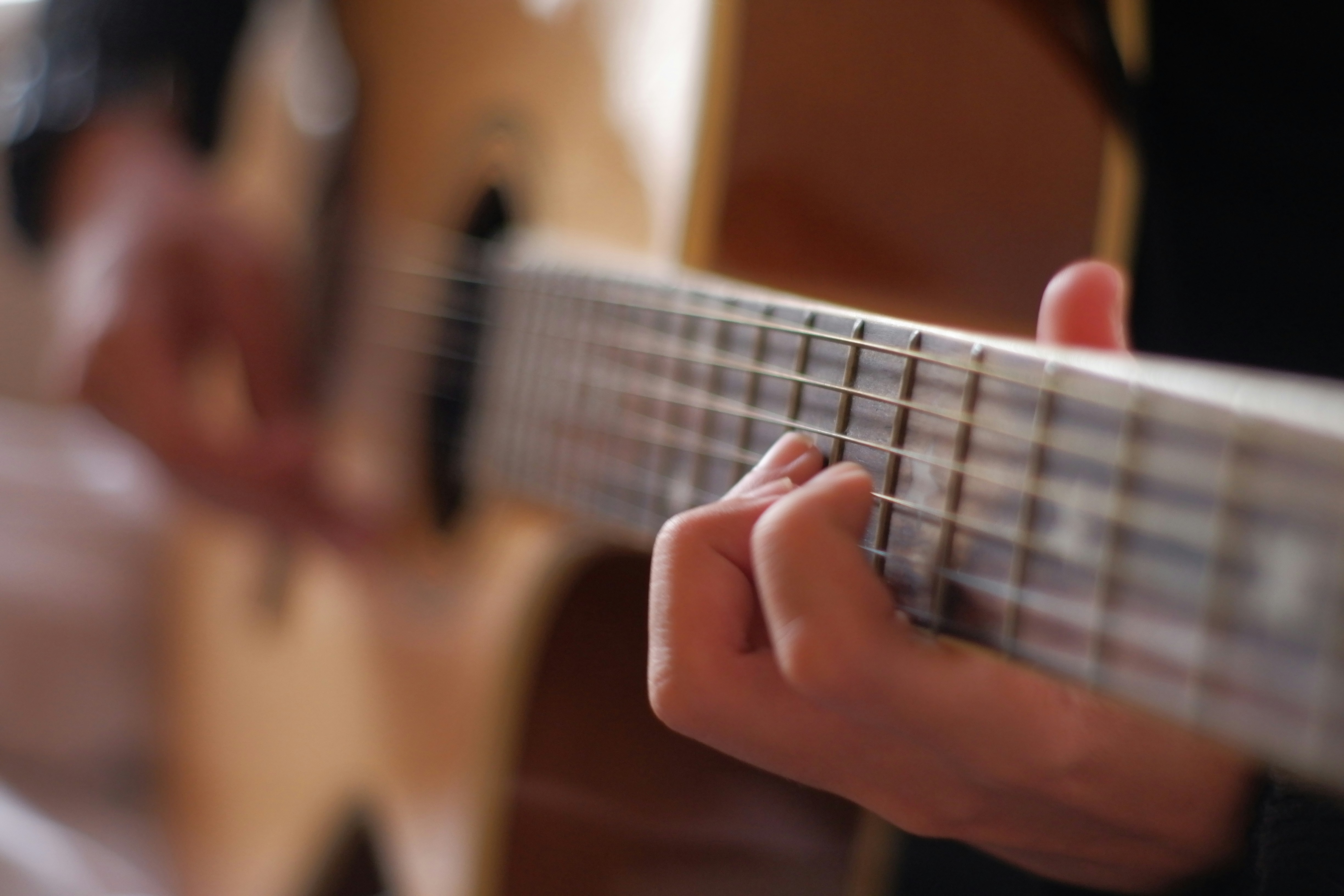 person playing brown acoustic guitar