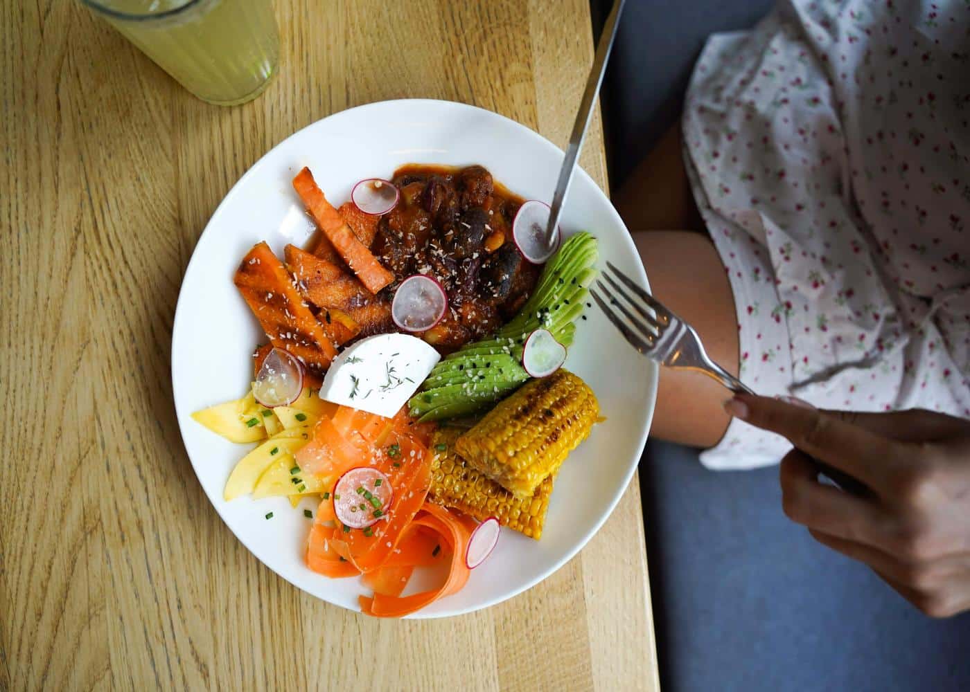 Person sitting in front of a white plate with veggies and fruits to showcase alkaline diet foods