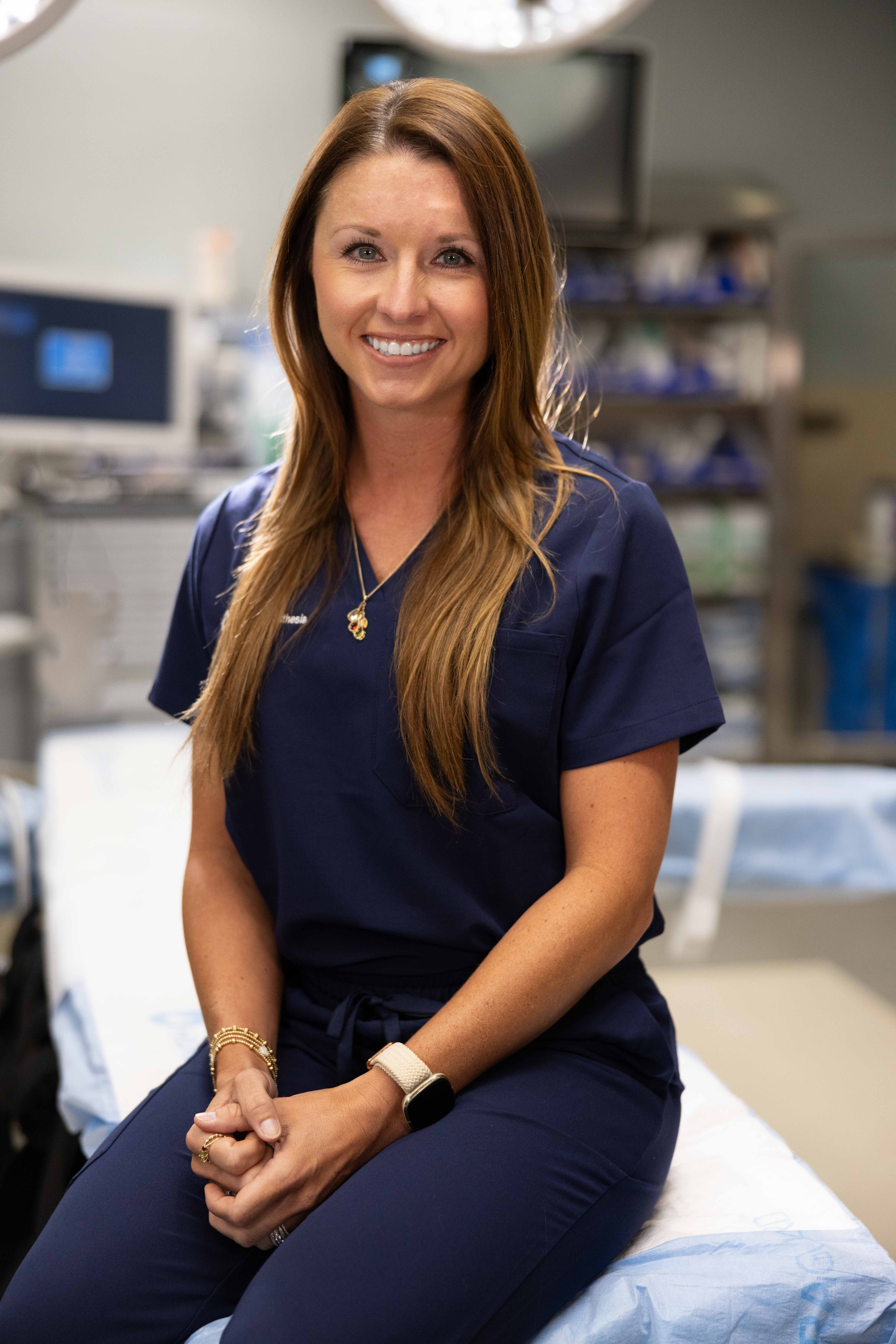 LifeLinc CRNA smiling in clinical scrubs inside a hospital operating room