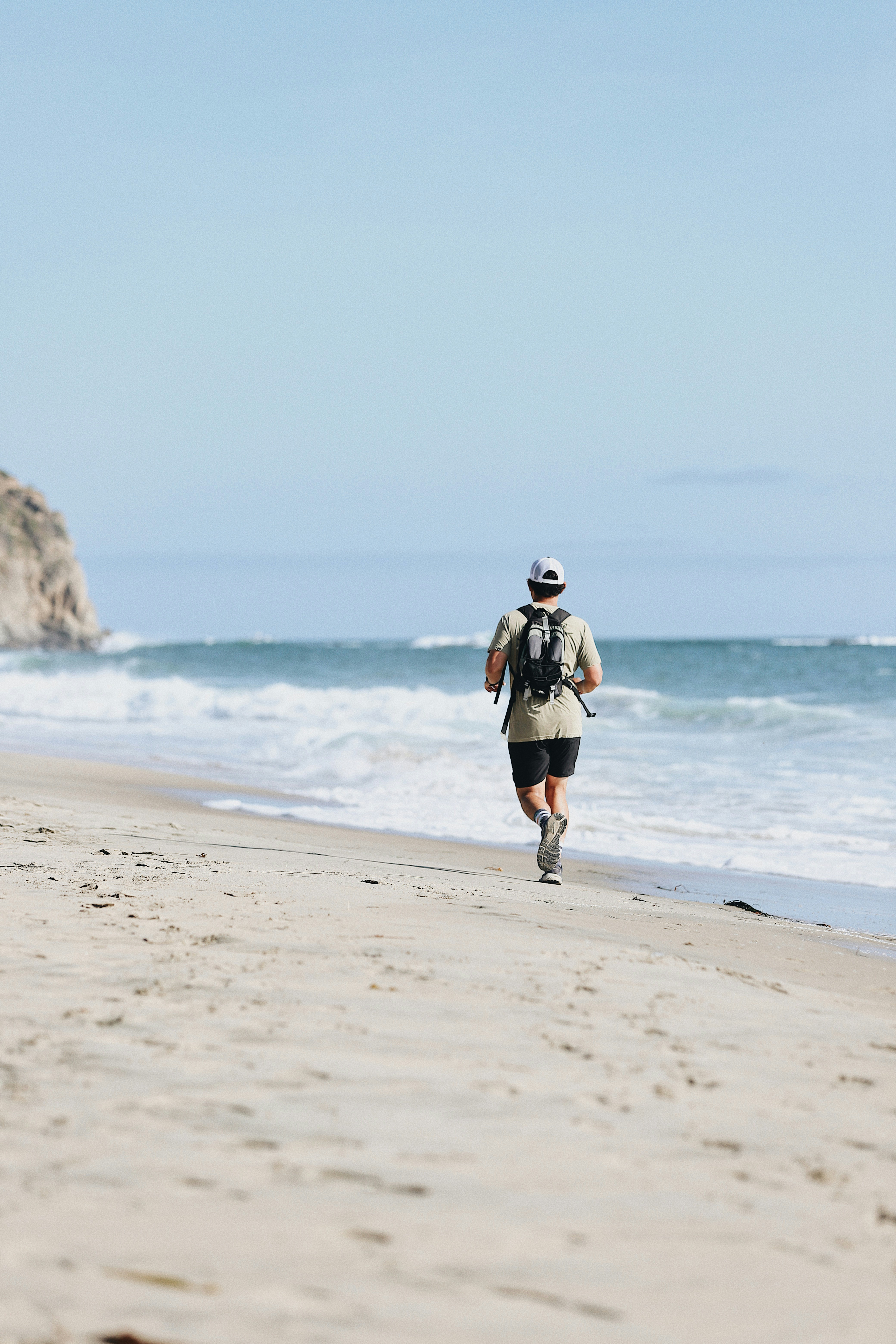 Runner training along the beach with the ocean in the background