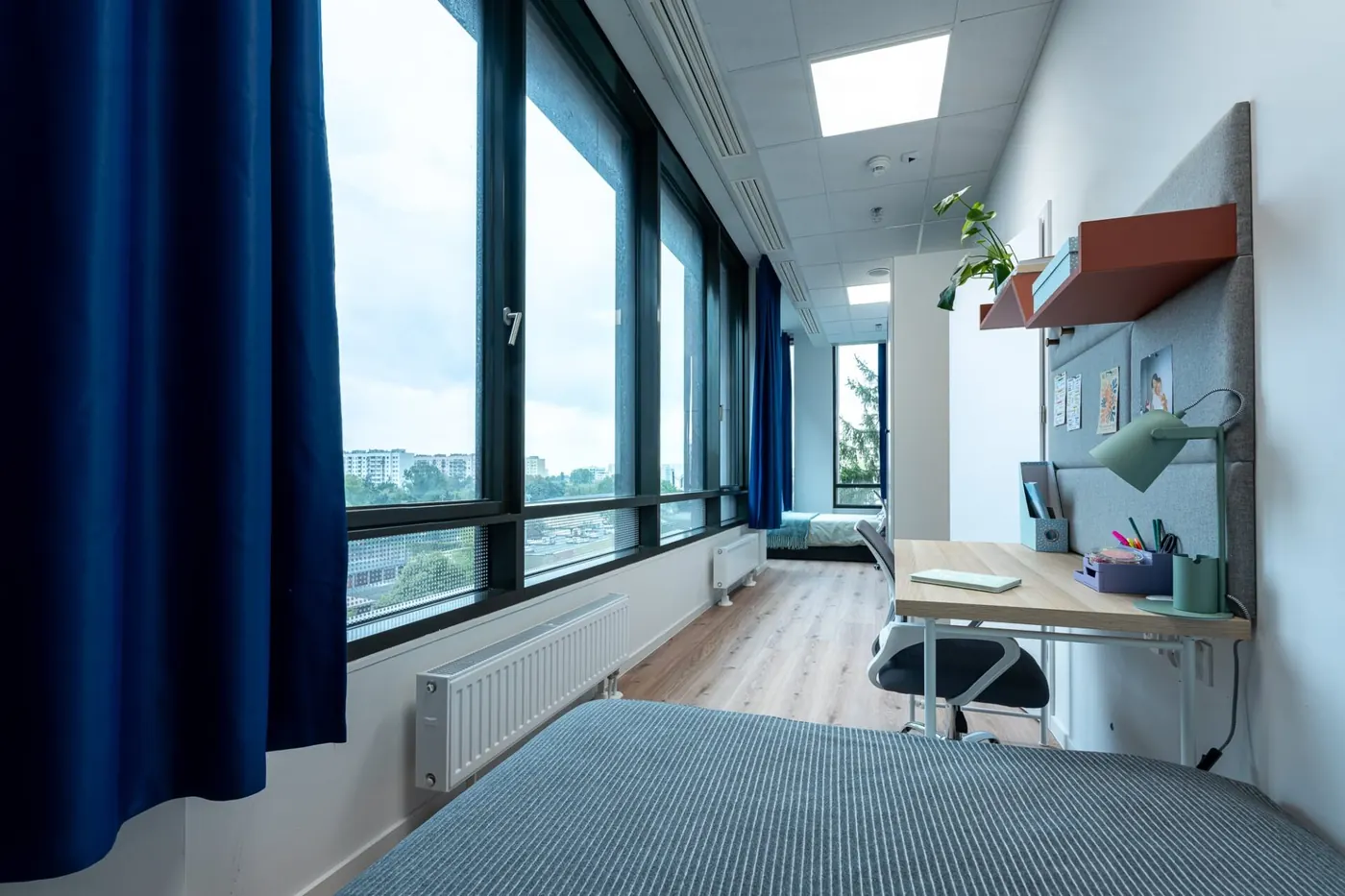 Student room in Warsaw accommodation with bed, study desk and large windows