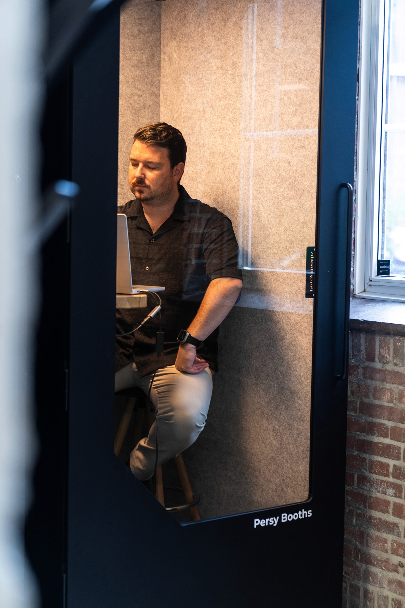 a man is locked up behind glass, we are not sure if he is there out of free will