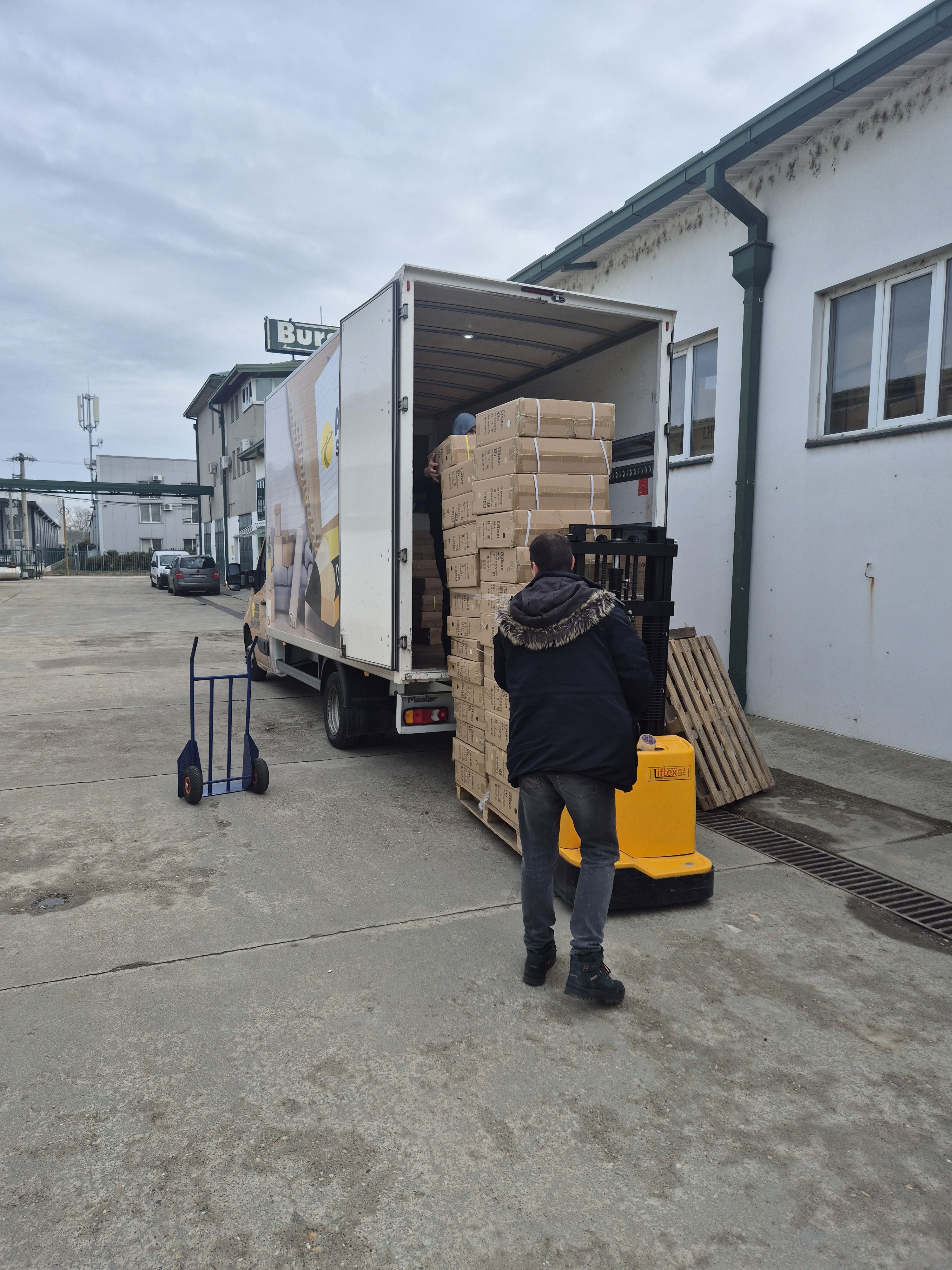 Istovar robe iz kamiona paletnim viljuškarom ispred skladišta.