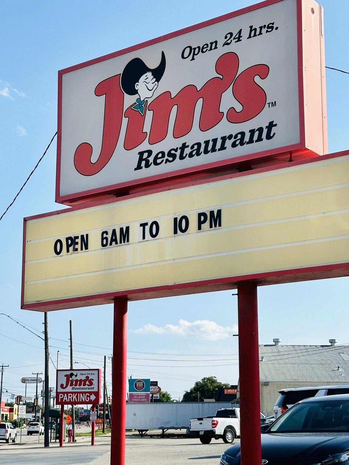 Jim’s Restaurant sign advertising Open 24 hrs. above a board reading OPEN 6AM TO 10 PM