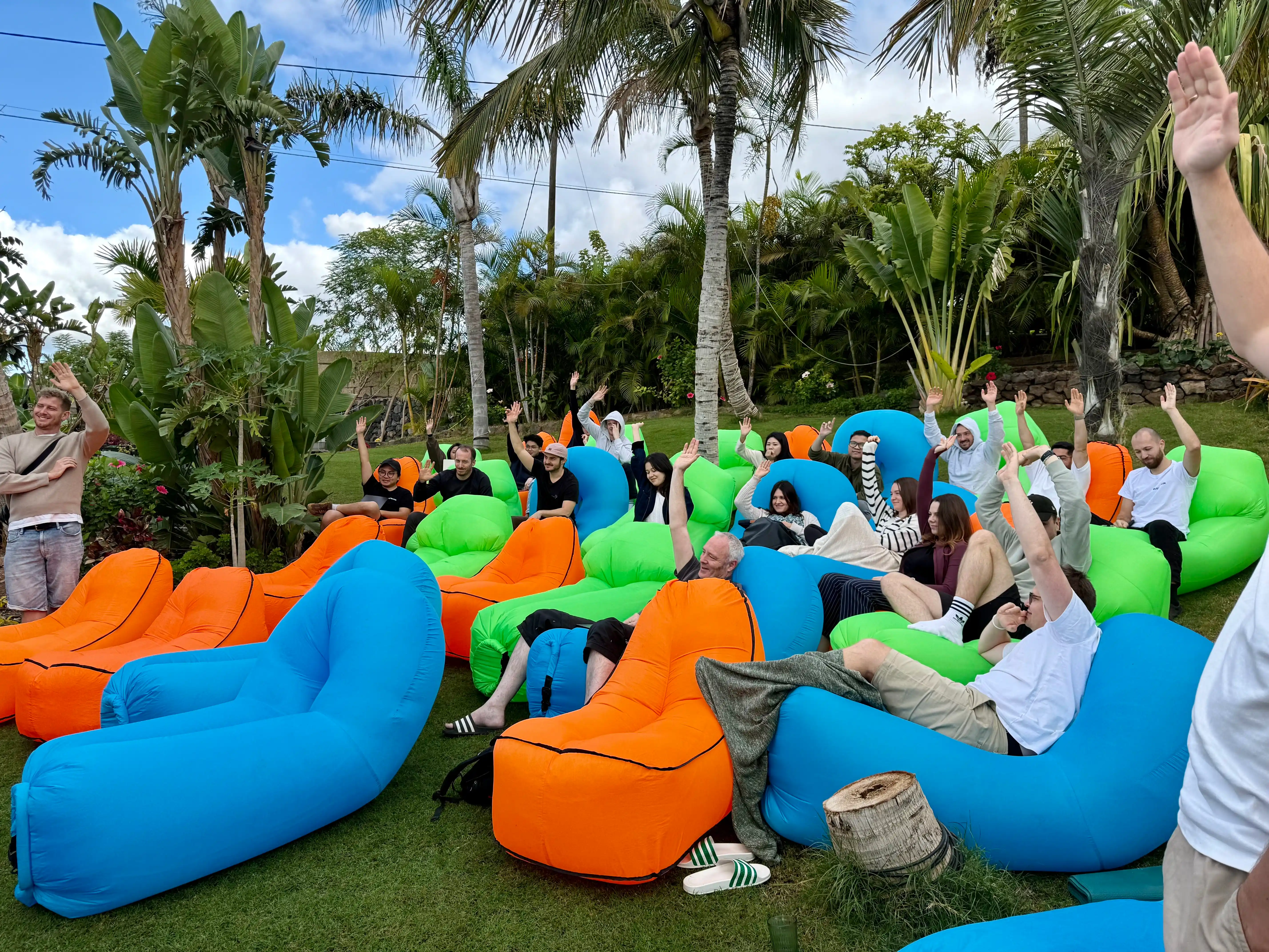 Team enjoying a retreat, sitting on colorful inflatable loungers in a tropical garden