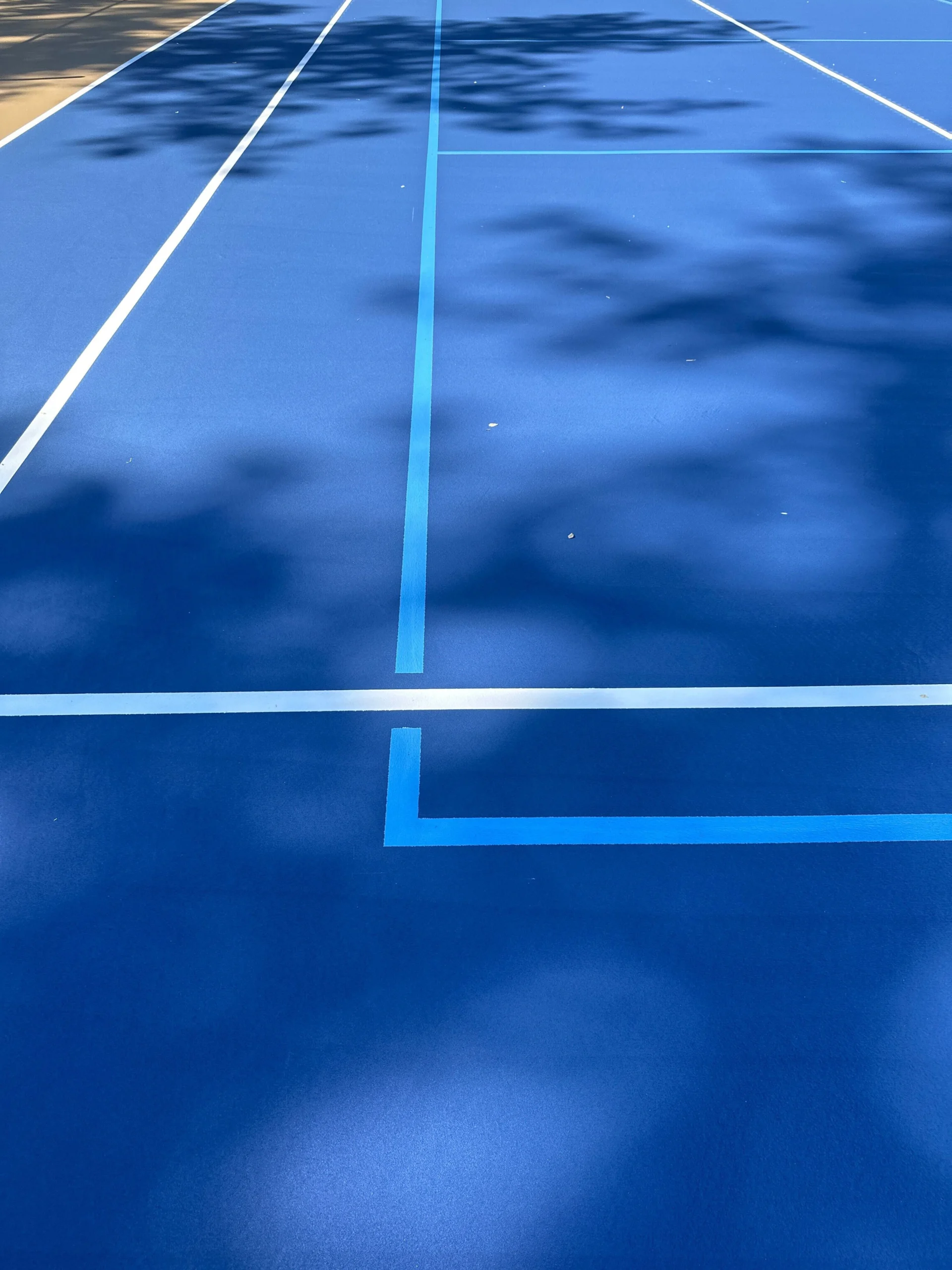 Close-up of light blue pickleball lines and white tennis striping on resurfaced court in Fort Mitchell, AL