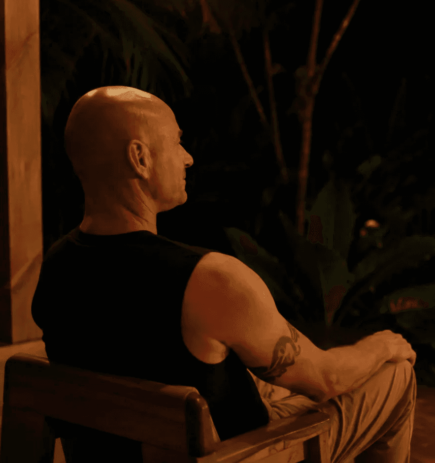 Maestro Sani seated beside a lantern overlooking the Costa Rican rainforest at night