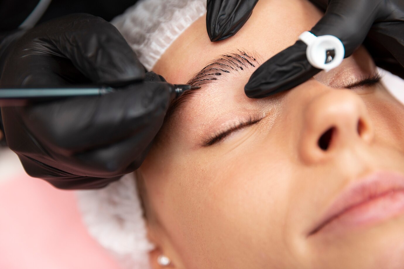 Woman receiving microblading treatment, showcasing eyebrow enhancement in a professional studio.