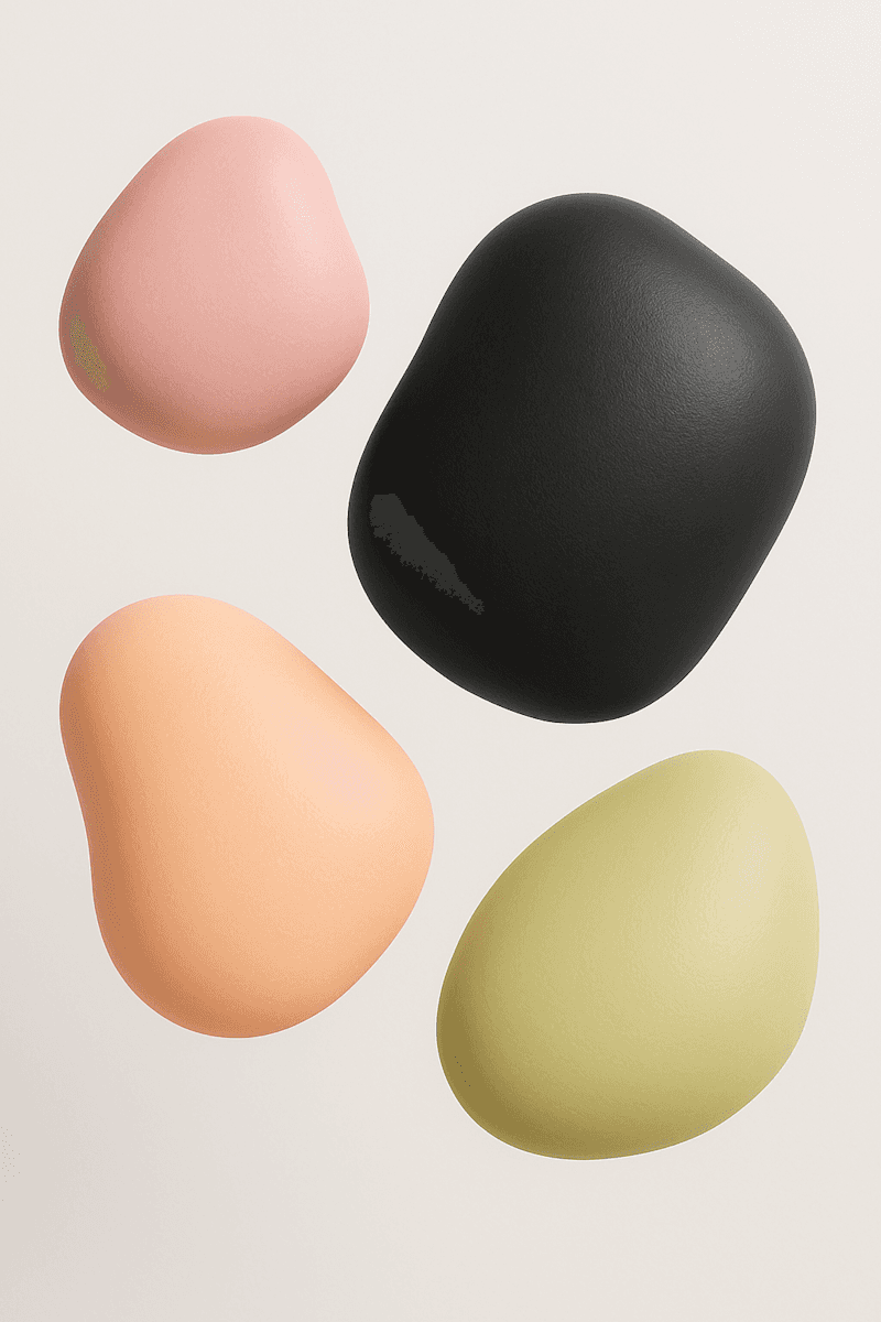 Four smooth eggs in muted tones of pink, green, peach, and black, showcased against a cream background for a minimalist aesthetic.