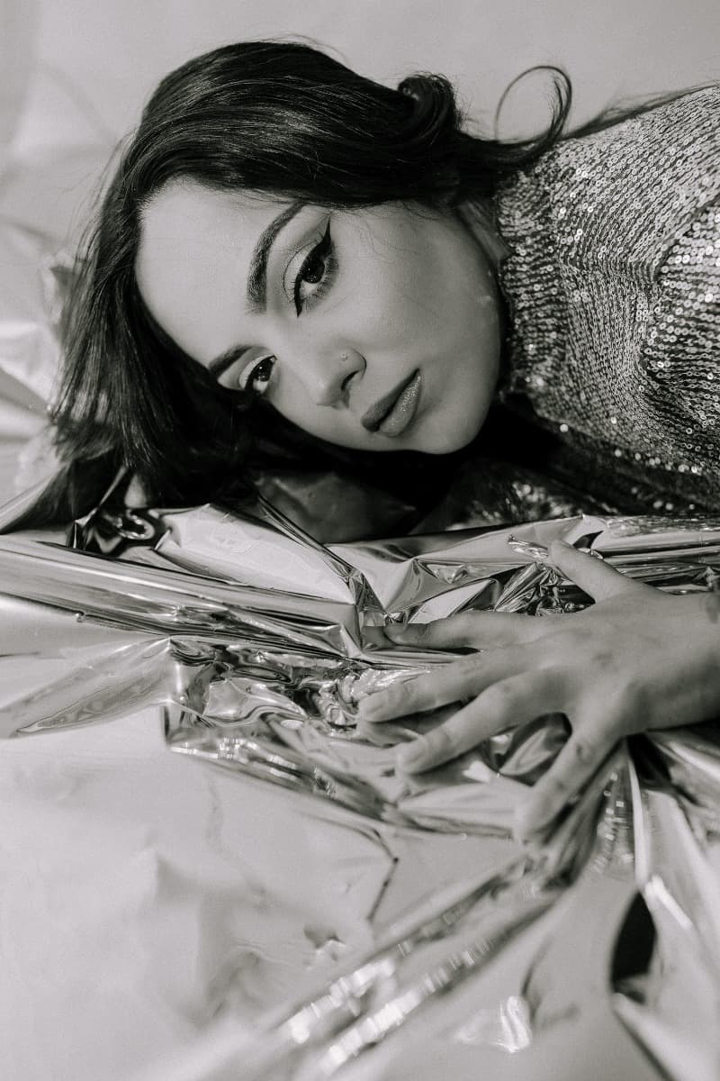 A model resting her head on reflective Mylar, gazing into the camera during a creative Mylar shoot at Revelator Studio, a Shreveport natural light photography studio.