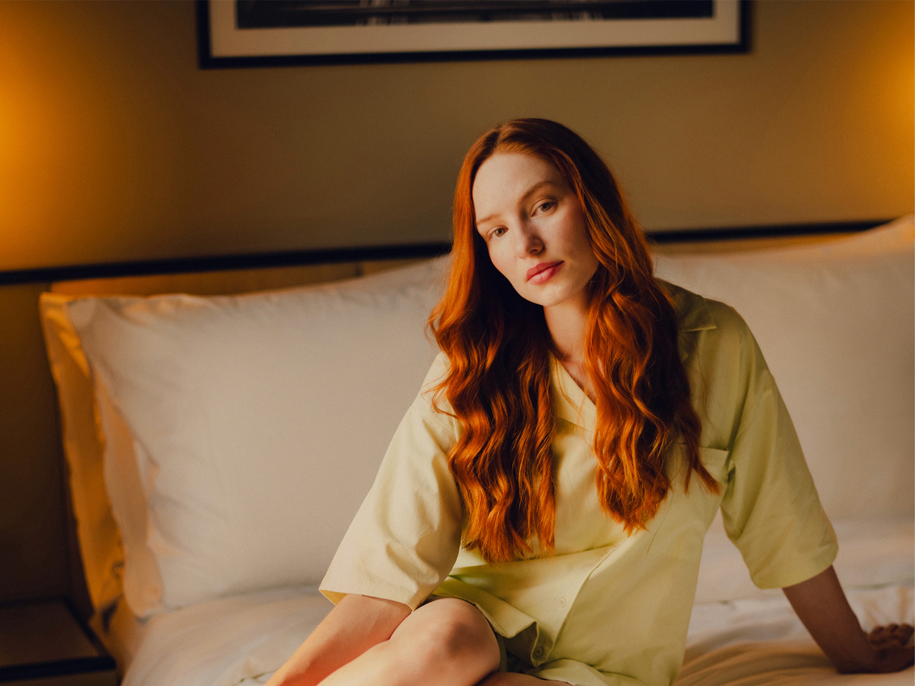 Red Headed woman sitting in bed in the Muse S room at The Companion Vienna