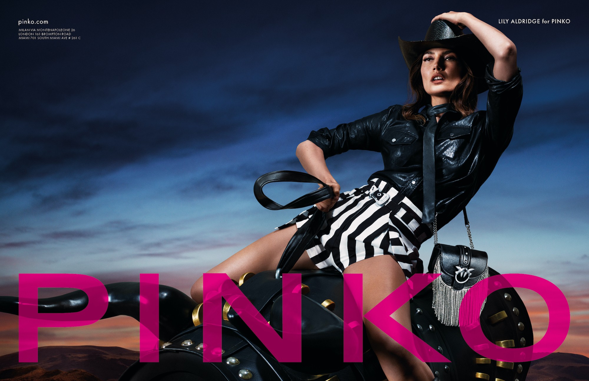 PINKO advertising featuring Lily Aldridge in contemporary western styling with leather jacket and striped accessories against dramatic sky backdrop with international flagship locations - 9-market digital property supervision and localized content strategy by Alessandro Brancati Marketing & Growth Studio