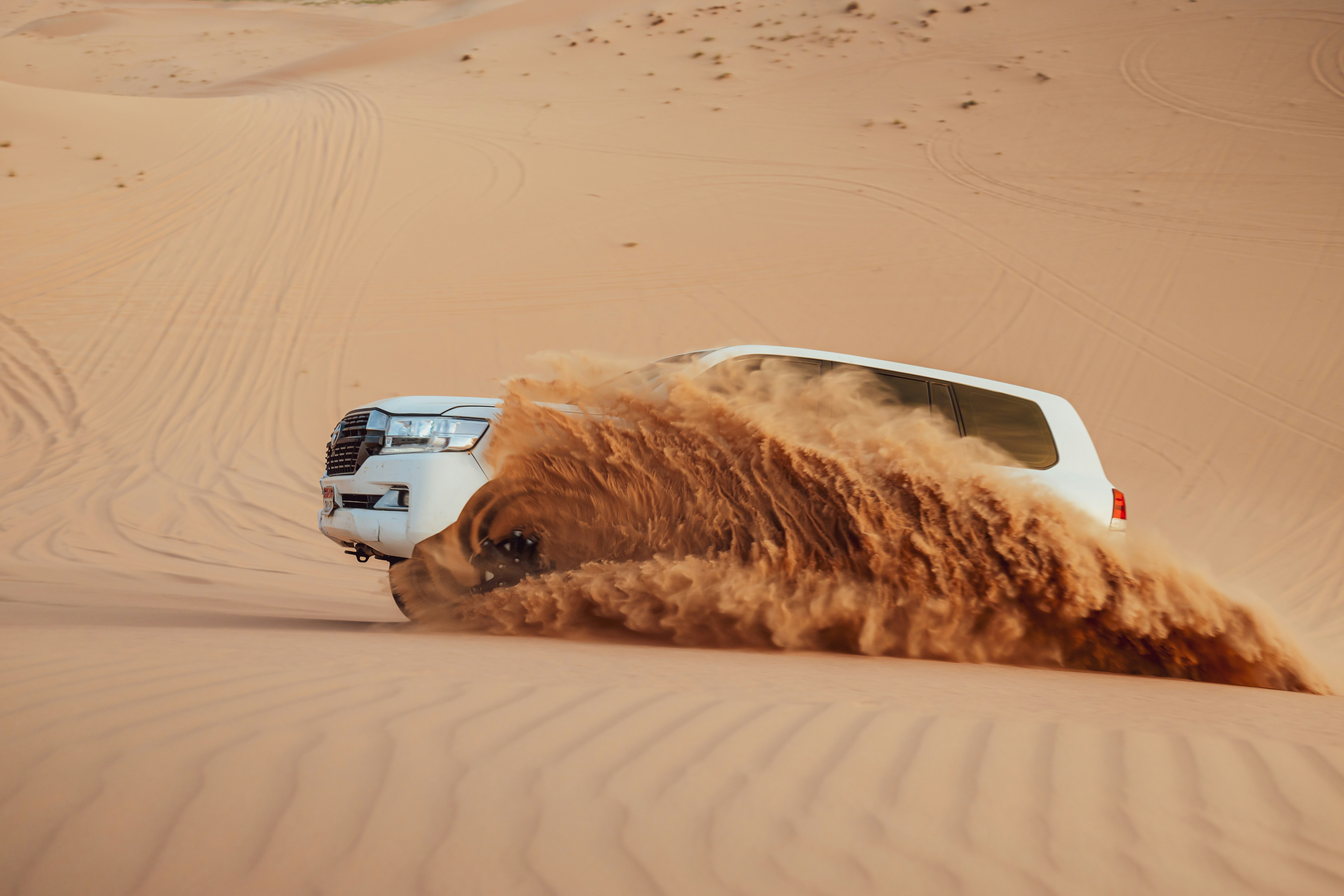 A car kicks up sand in the desert.