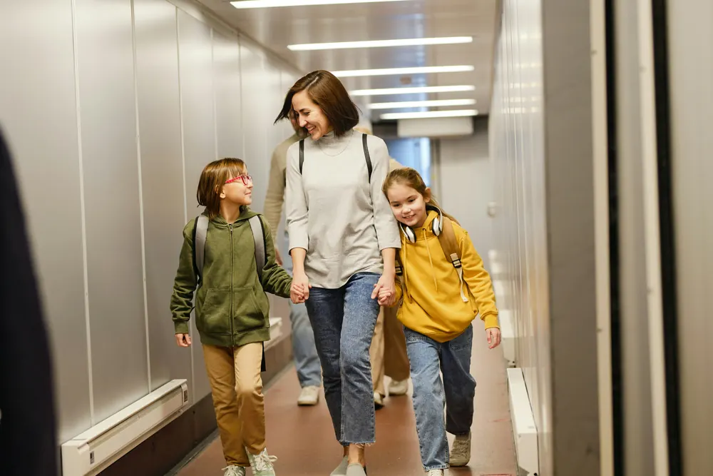 Mother and two children walking through an airport boarding bridge