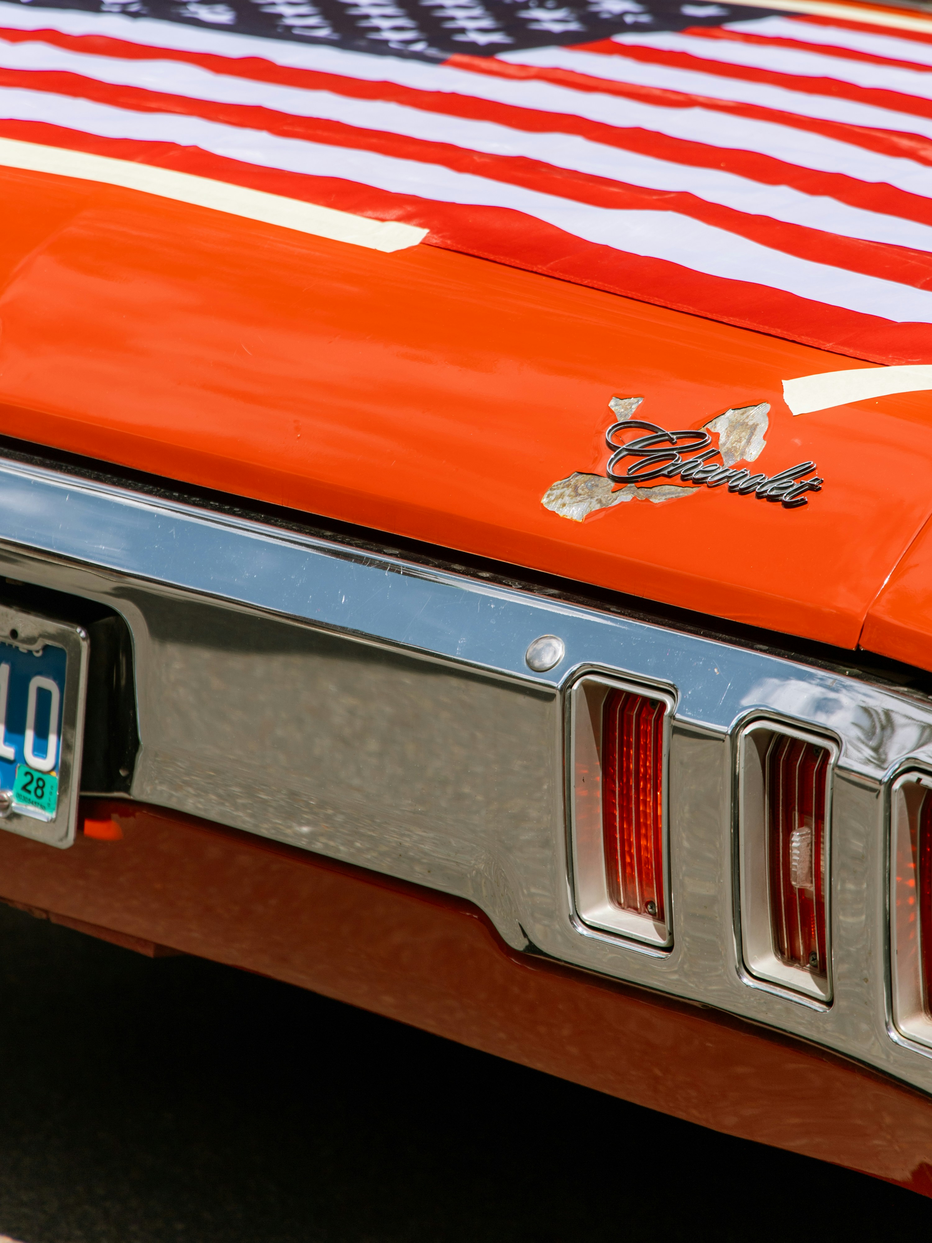 Orange car with american flag and chrome bumper