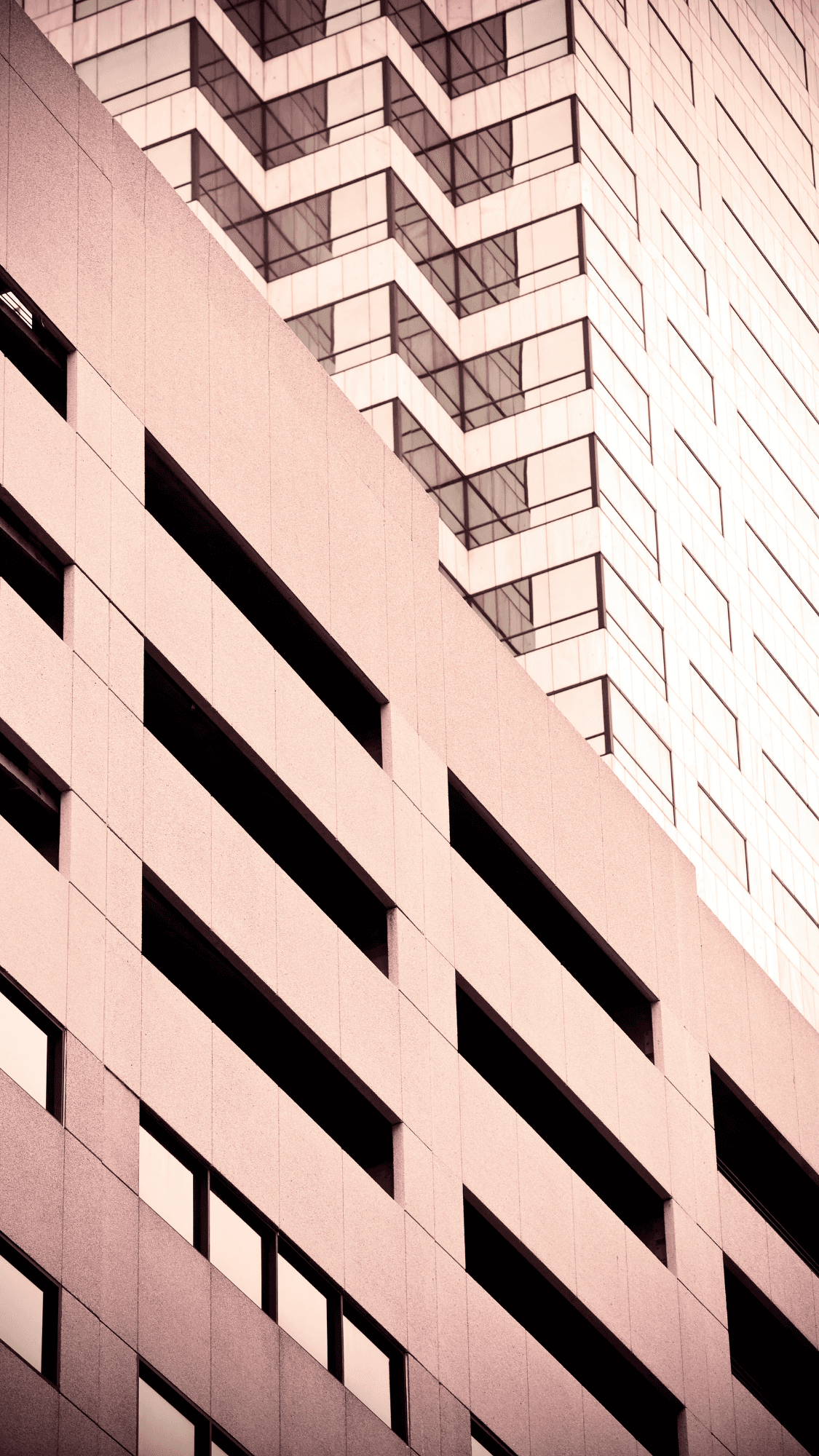 corner of Tall city buildings with architectural details photographed from below with bright sunlight in the background.